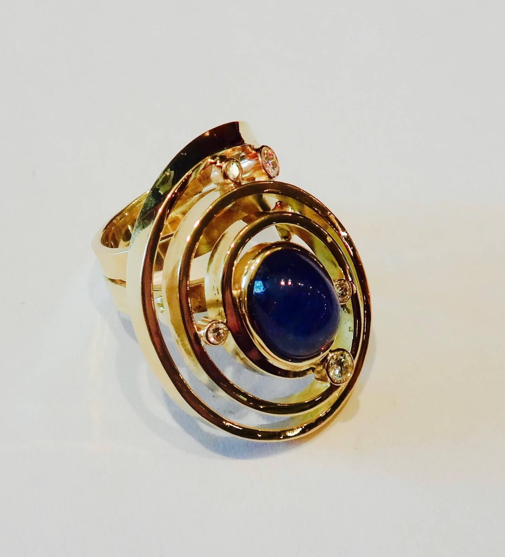 Inspired by the jewelry designs of Alexander Calder and specifically his wedding bands, this ring is fabricated for one continuous strip of hammered 18k yellow gold.  Set within the ring is an oval cabochon blue sapphire and 6 bezel set white