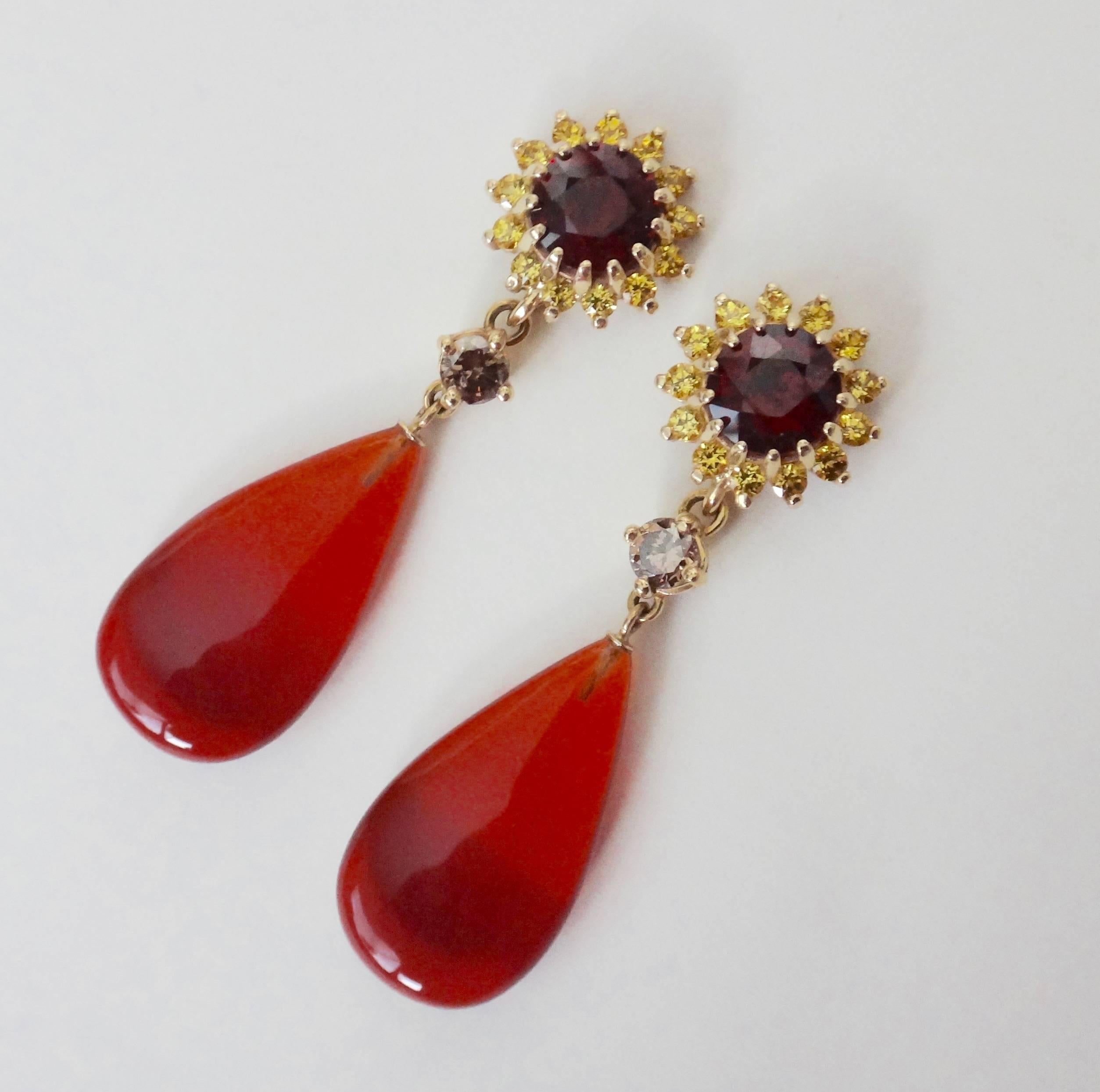 Brilliant cut Almandine garnets (Origin: Sri Lanka) are surrounded by bright yellow sapphires and further decorated with cognac colored diamonds and a very unusual pair of perfectly matched Mexican fire opals.  The highly polished drops are