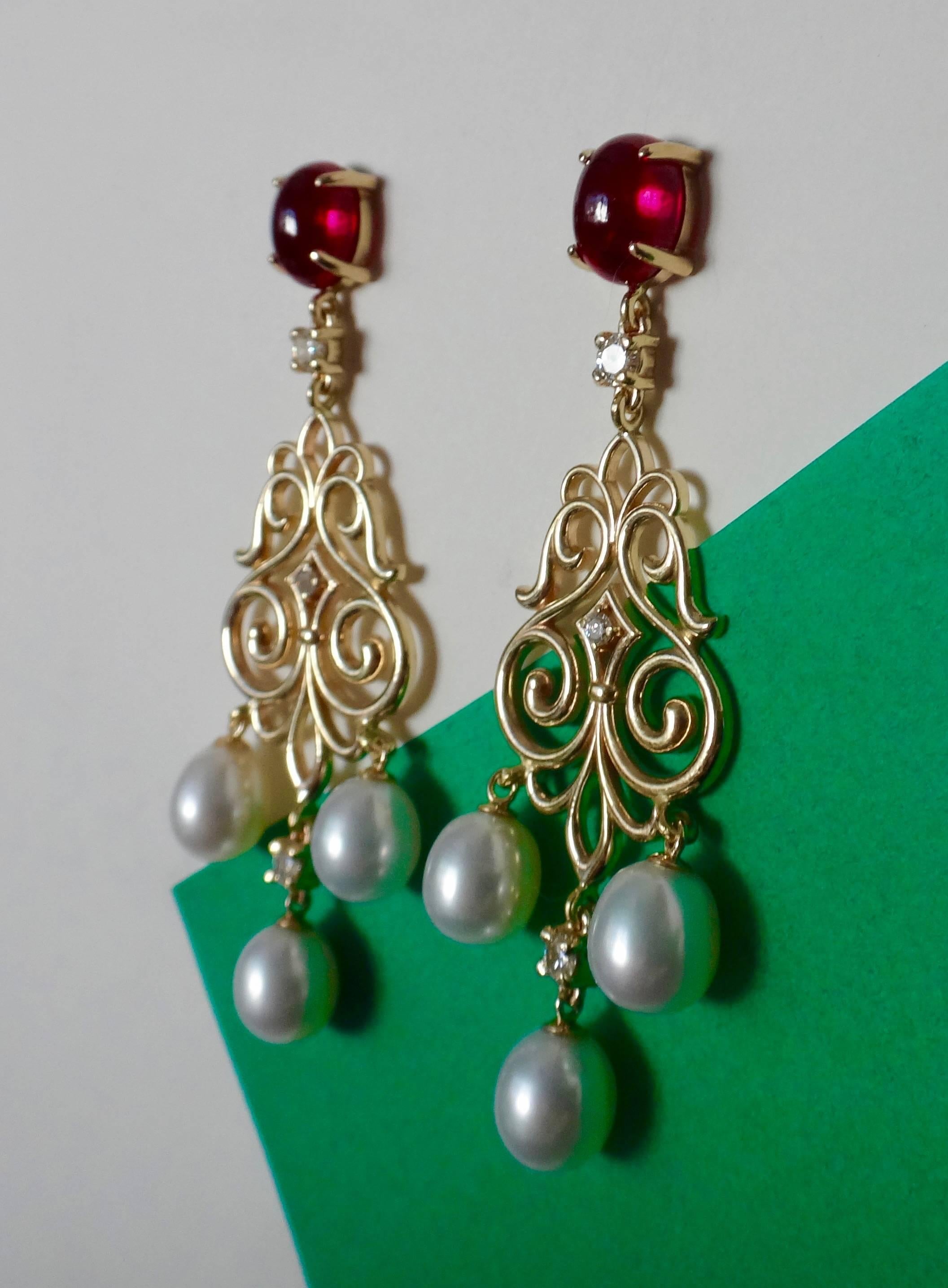 A pair of very fine cabochon rubellite tourmalines with beautiful red color and superb polish are combines with brilliant cut white diamonds and pear shaped white cultured pearls in these filagree dangle earrings. The earrings come with posts and