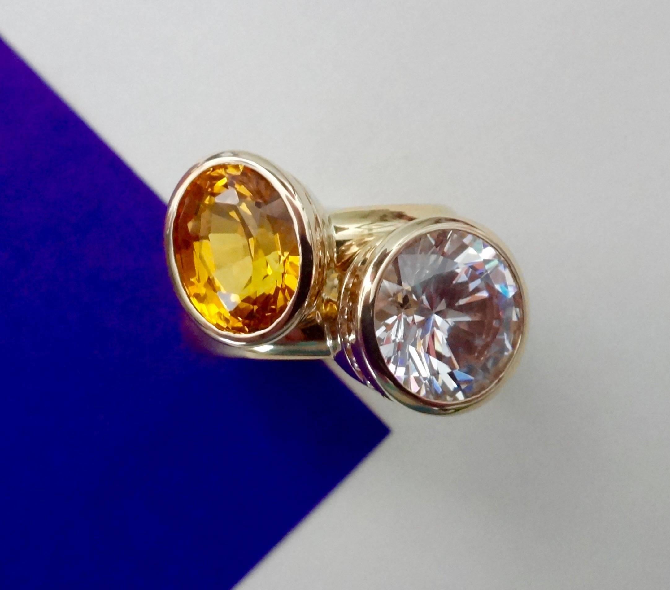 Oval cut and intensely colored yellow sapphire combined with a brilliant cut silver sapphire are set in a pair of 18k yellow gold stacking 