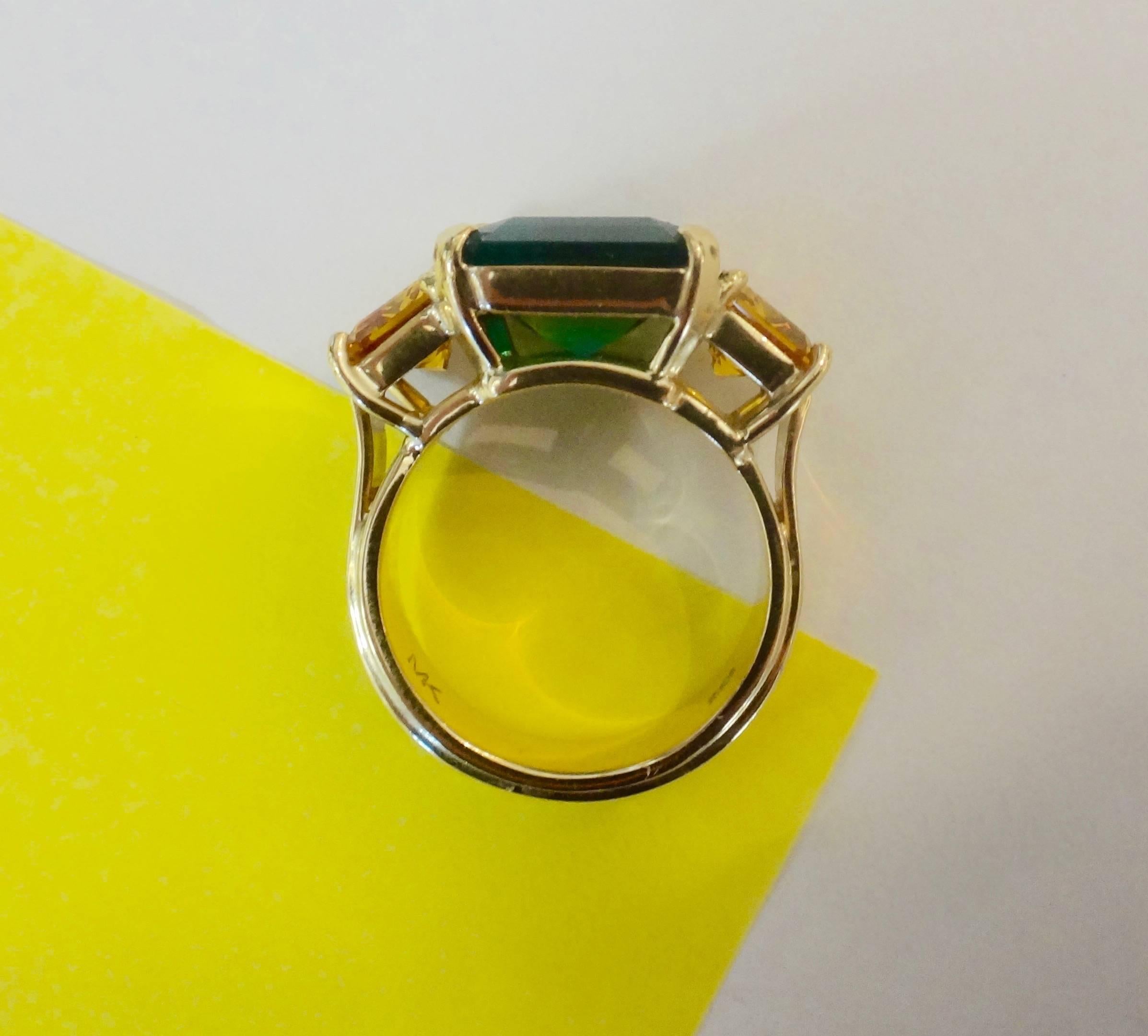 A square cut Zambian emerald is flanked by an intensely colored and well matched pair of emerald cut yellow sapphires in this handmade 18k yellow gold three stone ring.  The ring is a size 7 and is easily sized.  