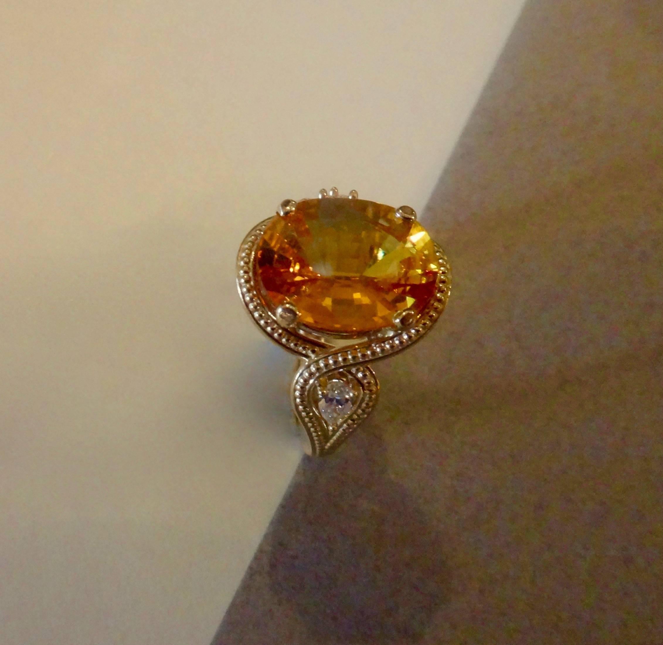 An oval cut, saffron yellow sapphire is enhanced with two pear shaped diamonds in this classic and tailored three stone ring.  Beaded detail further embellishes the piece.  Ring size 7 and is easily sized.  