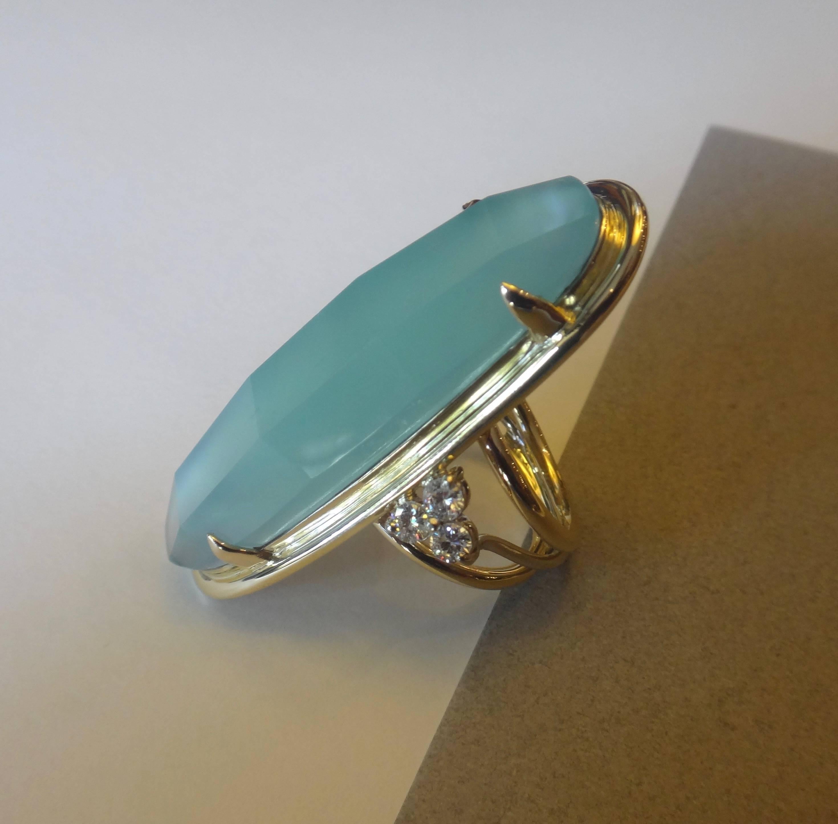 An exaggerated oval of a faceted and pearlescent aquamarine is complimented with diamonds in this most unusual cocktail ring.  The setting is hand made in 18k gold.  The ring is a size 7 and is easily adjusted.  
