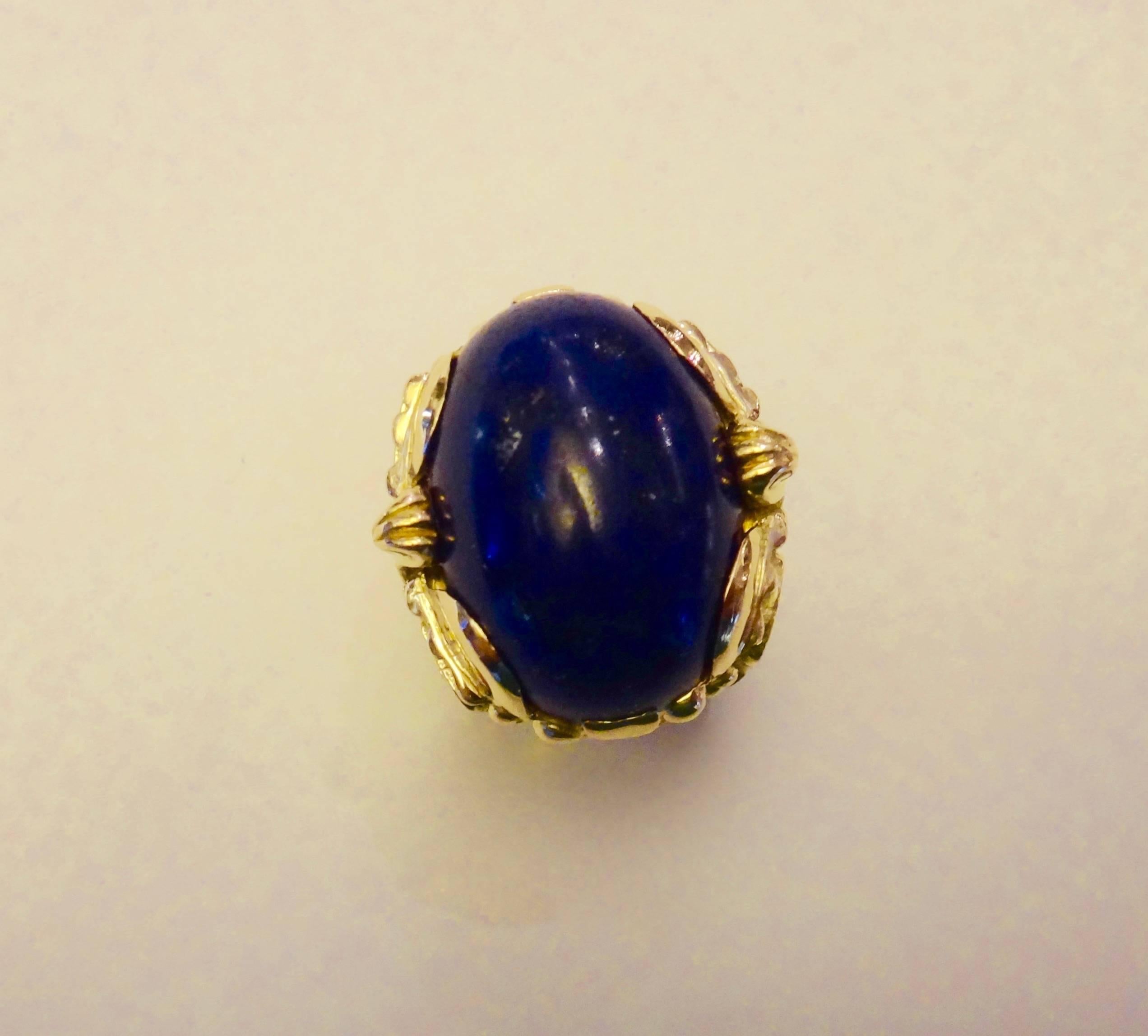 A large cabochon of Lapis Lazuli is set in this heavy 18k yellow gold ring by legendary goldsmith Norah Pierson of the Golden Eye located in Santa Fe, New Mexico.  The mounting has powerfully sculpted Aztec influenced images.  Ring size 8 and may to