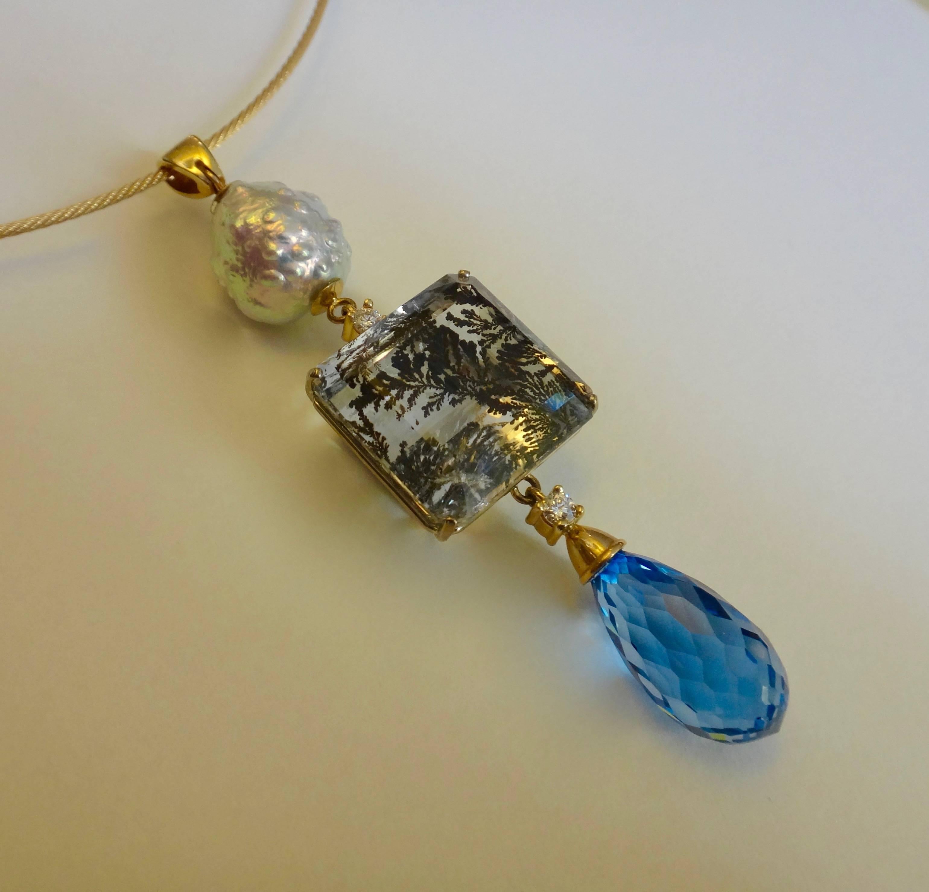 A rare and fabulous dendritic quartz is the featured centerpiece in this pendant.  The fern-like inclusions are formed from captured iron oxide within the clear quartz.  Enhancing the center stone is a metallic finished Kasumi pearl, a blue topaz