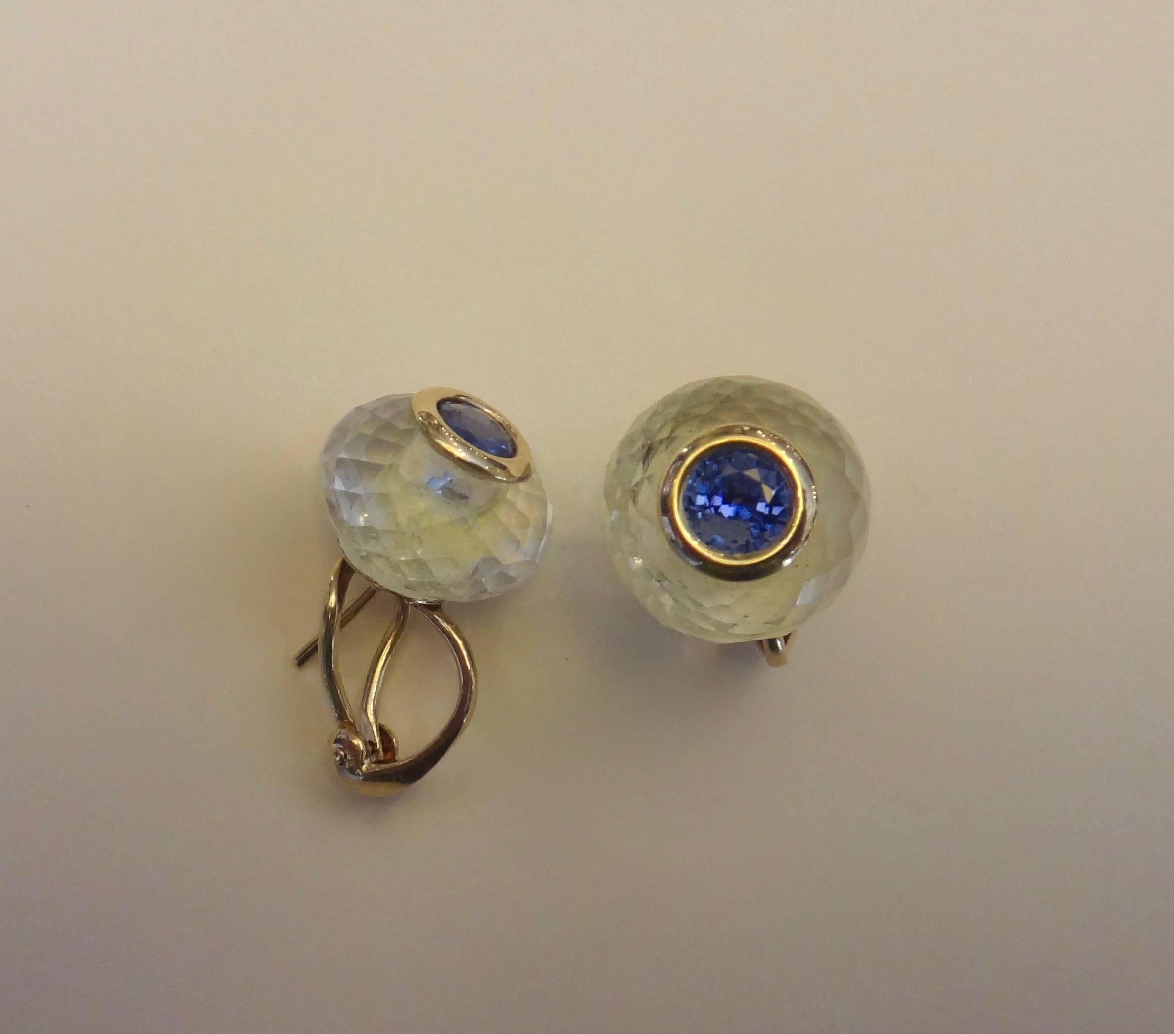 Brilliant cut and bright blue sapphires are bezel set within faceted rock crystal rondelles in these classic and emminently wearable stud earrings.  The earrings have posts with omega clip backs for safety.  