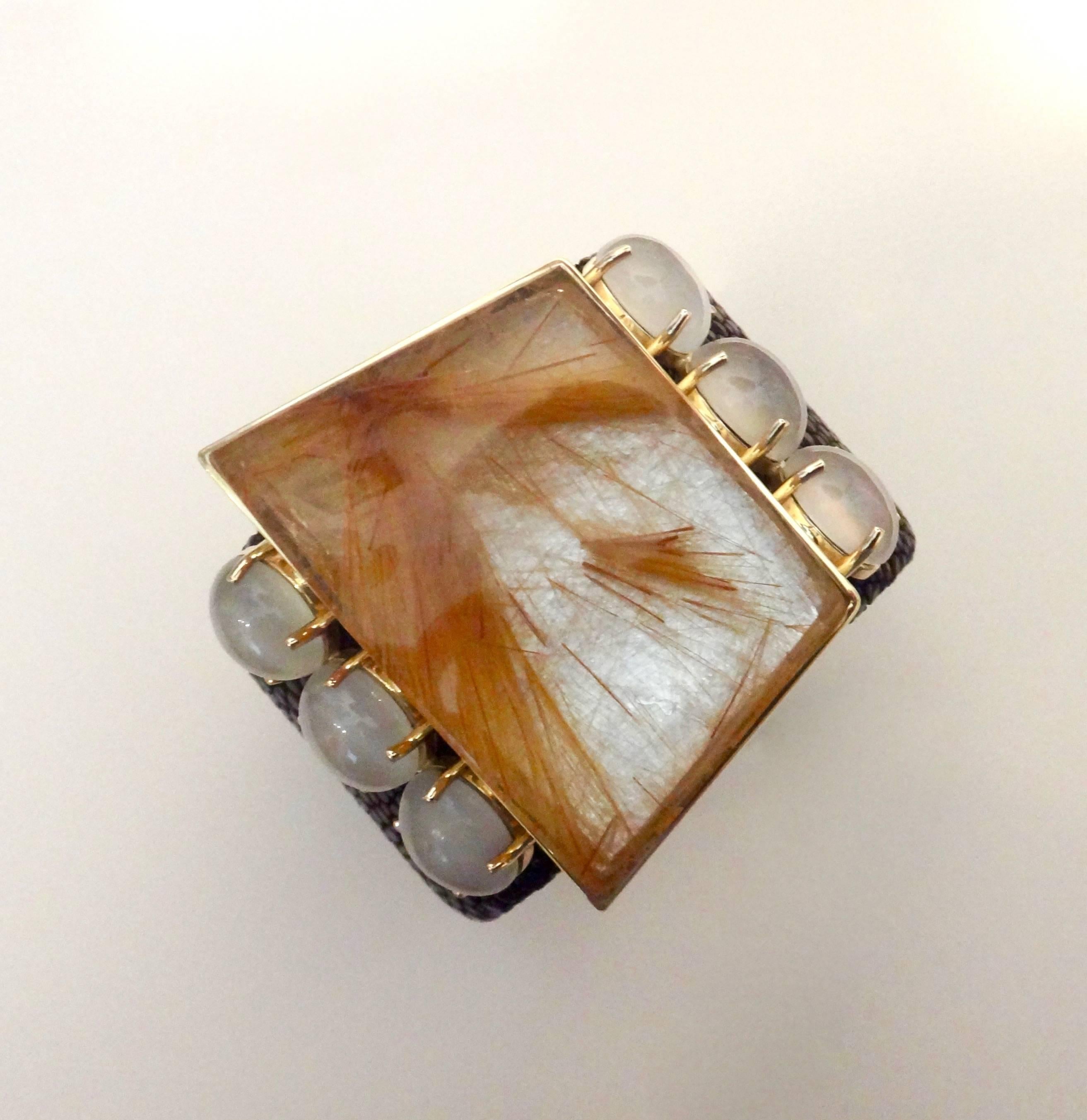 A fantasy cut slab of rutilated quartz is embellished with six striking white and perfectly matched moonstones in this dramatic cuff bracelet.  Rutilated quartz is a type of quartz with needle-like rutile embedded within it.  All the gems are set in