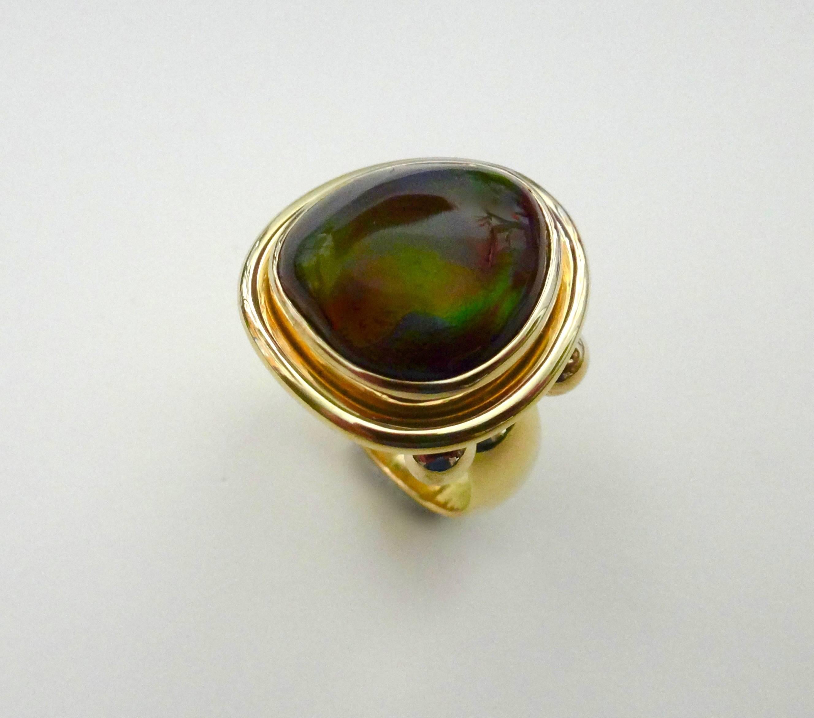 A superb example of Mexican Fire Agate is set in a handmade 18k yellow gold ring.  The gem has a remarkable range of colors including orange, green, gold, blue and even a hint of purple, the rarest color in this type of agate, all in a brown body. 
