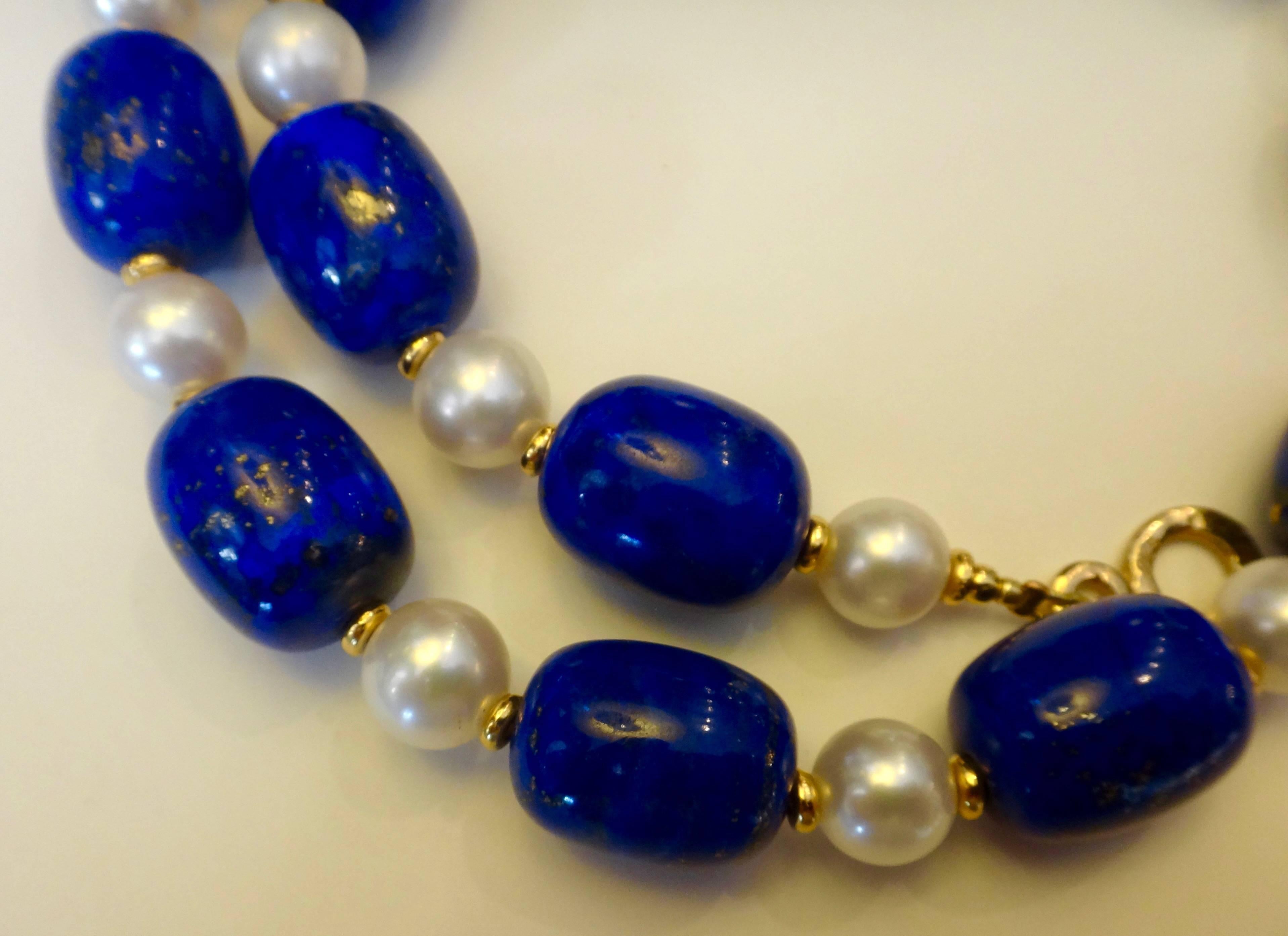 Lapis lazuli rough from Afghanistan has been shaped and polished into barrel shaped beads and are classically combined with gem quality white cultured pearls in this necklace.  The lapis is a highly polished royal blue and sprinkled with pyrite, so