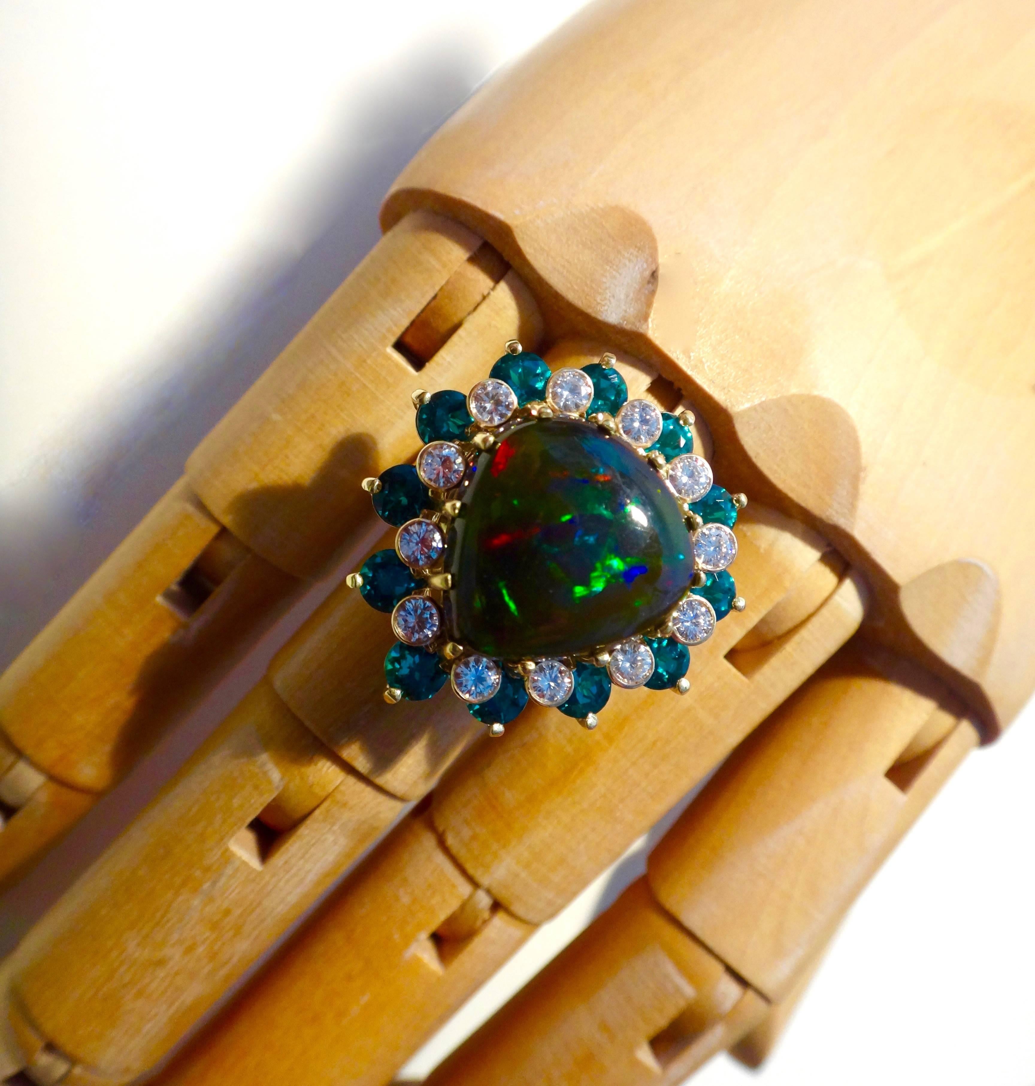 An Ethiopian black opal is the centerpiece of this bold and dramatic cocktail ring.  The pear shaped gem has a dark green/black matrix with a broad range of colors that flash and glitter as the ring moves.  The opal is complimented with rows of