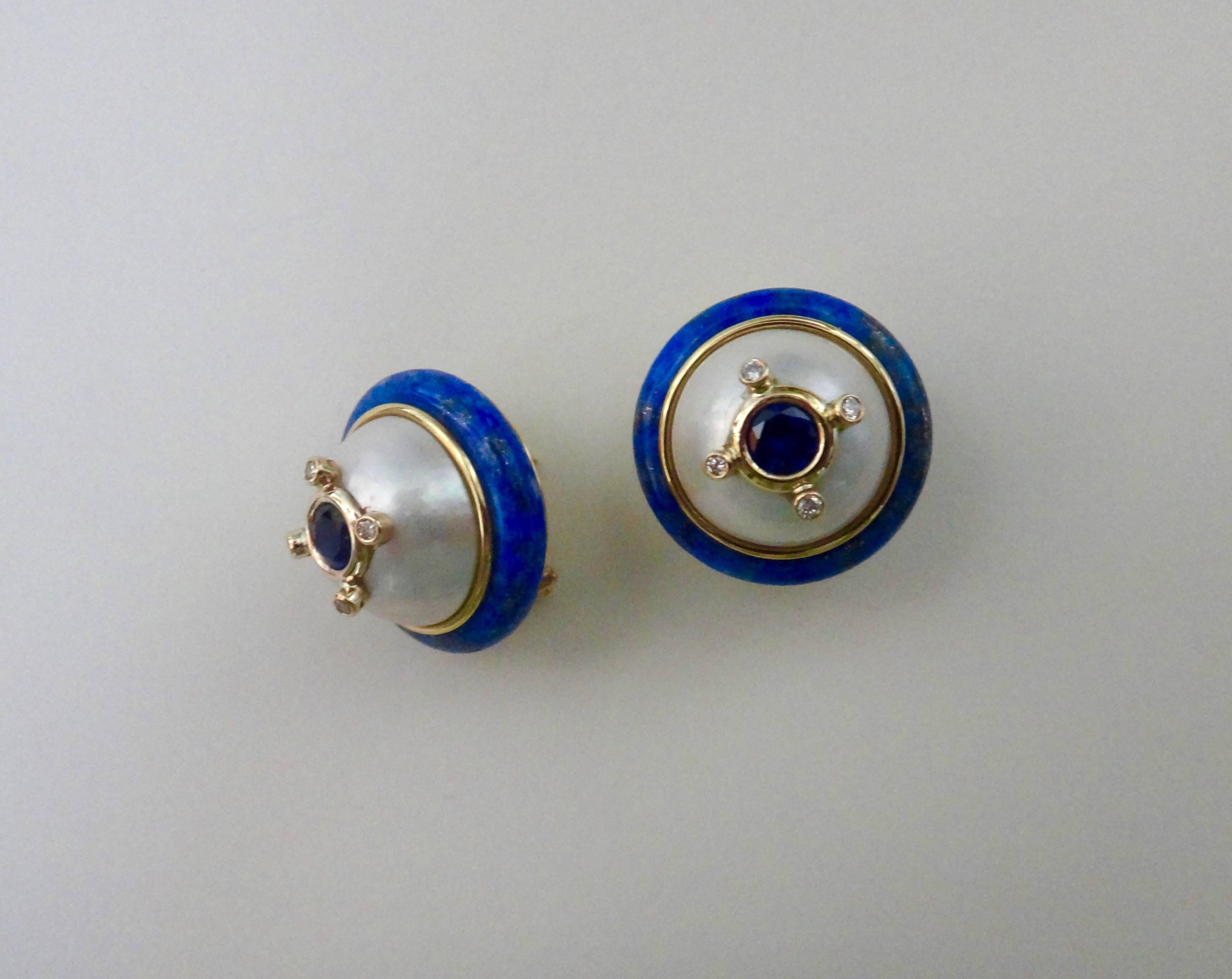 Blue sapphires are bezel set and embellished with white diamonds, all of which are mounted on a huge pair of mobe pearls. The compositions are framed with lapis lazuli in these stylish button earrings.  The mountings are fabricated in 18k yellow
