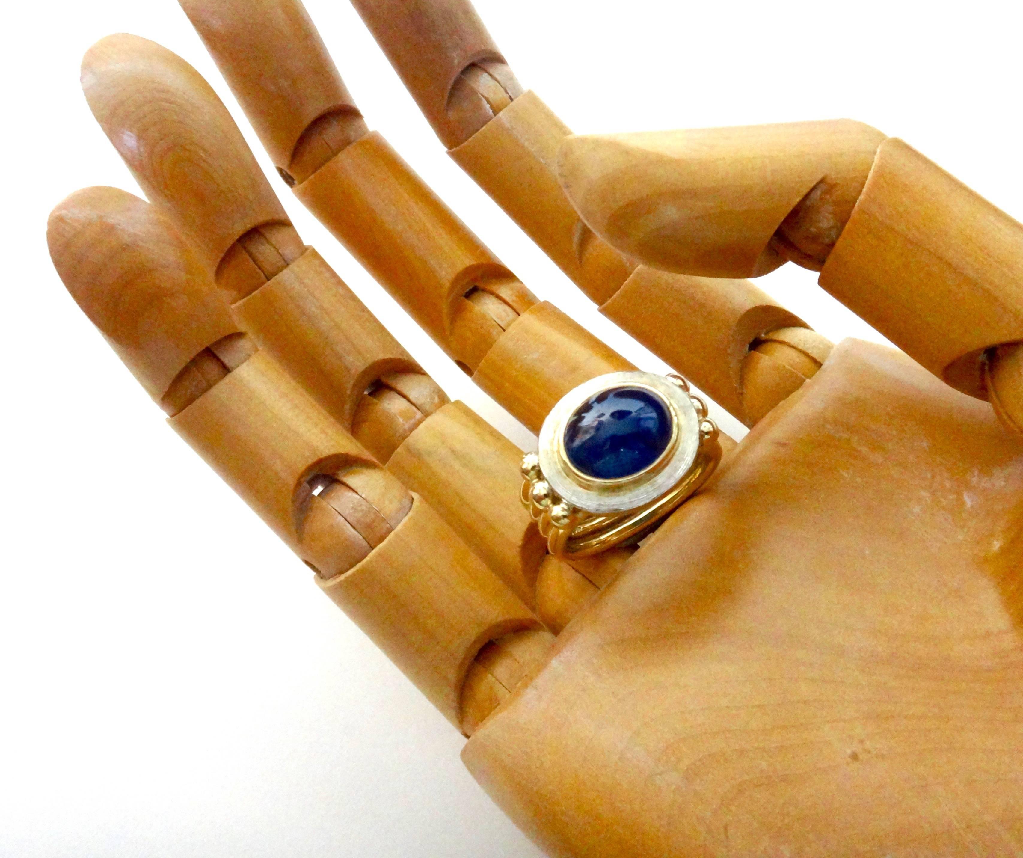 Calling attention to jewelry designs from centuries past, this "Relic" ring is set with a dark blue cabochon sapphire.  (Origin: Thailand)  A highlight of the ring is the Florentine engraving around the white gold bezel which catches and