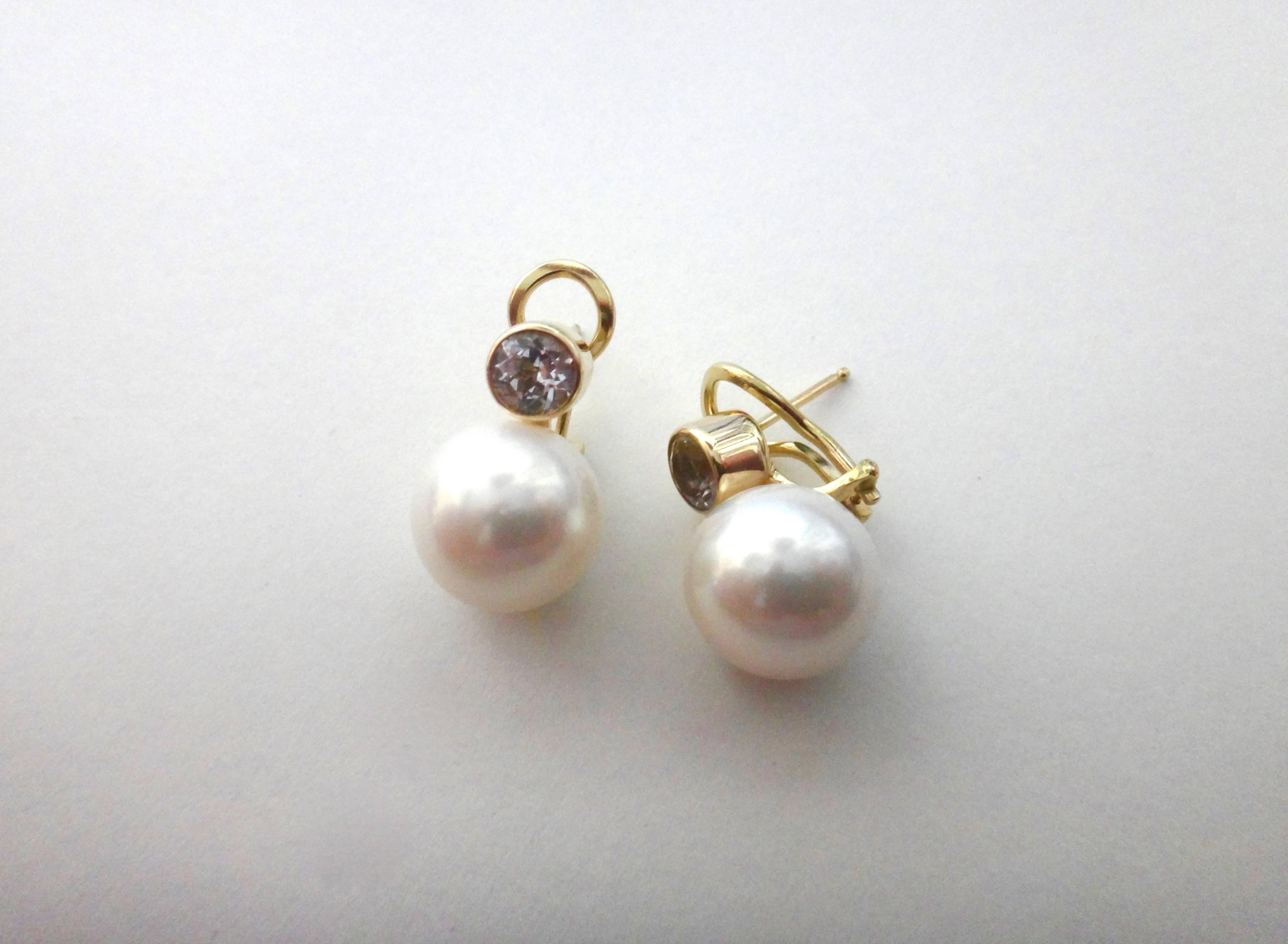 Silver sapphires in a brilliant cut are bezel set and sit atop a pair of fashion quality 12.5mm white South Seas pearls in these classic stud earrings.  Set in 18k yellow gold, the earrings have posts with omega clip backs for comfort and safety. 
