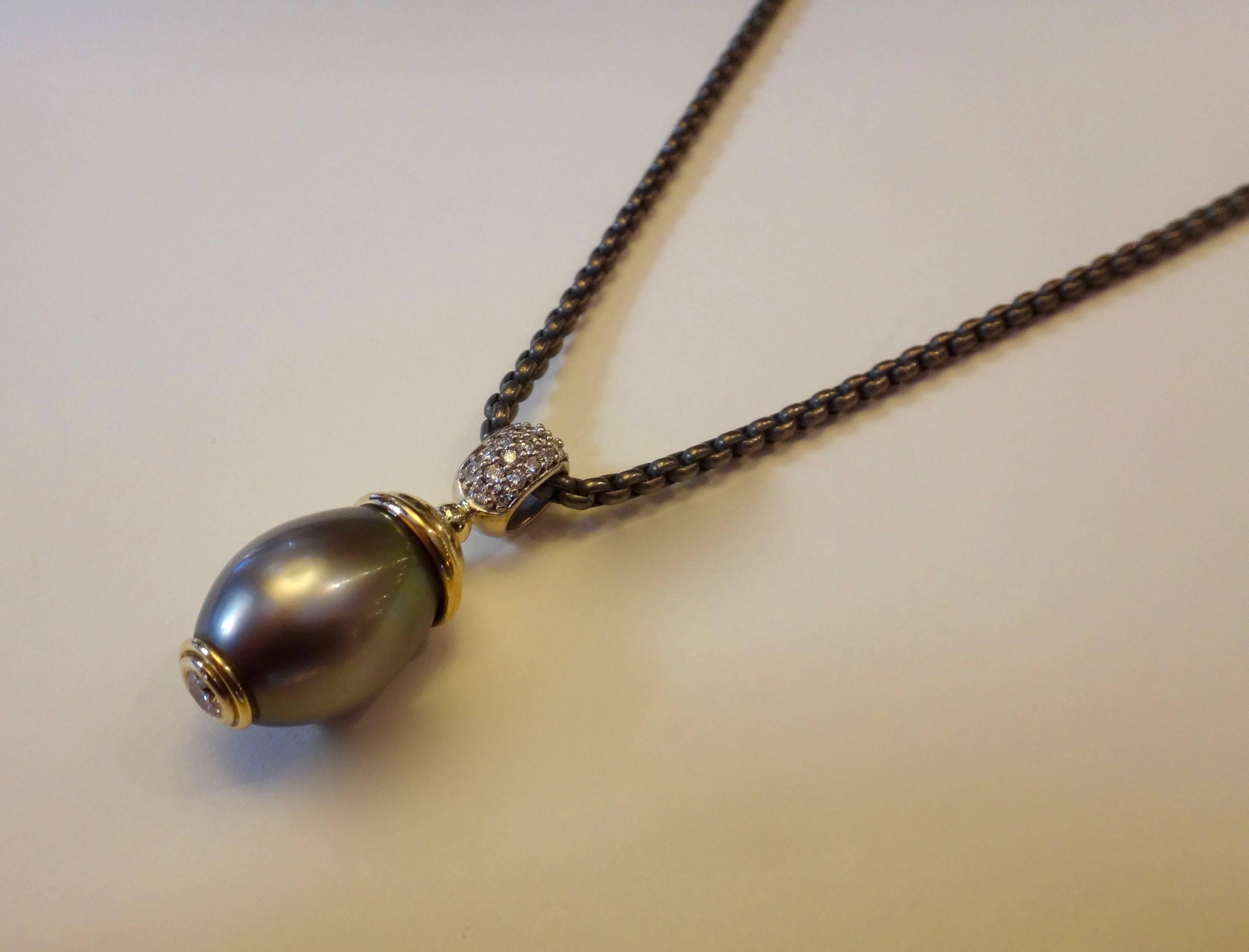 Reminiscent of the egg pendants created by the great House of Faberge in the previous century, comes this Tahitian pearl pendant.  The gem quality pearl is of a medium gray color, possesses a silky luster and reflects a range of peacock colors.  The