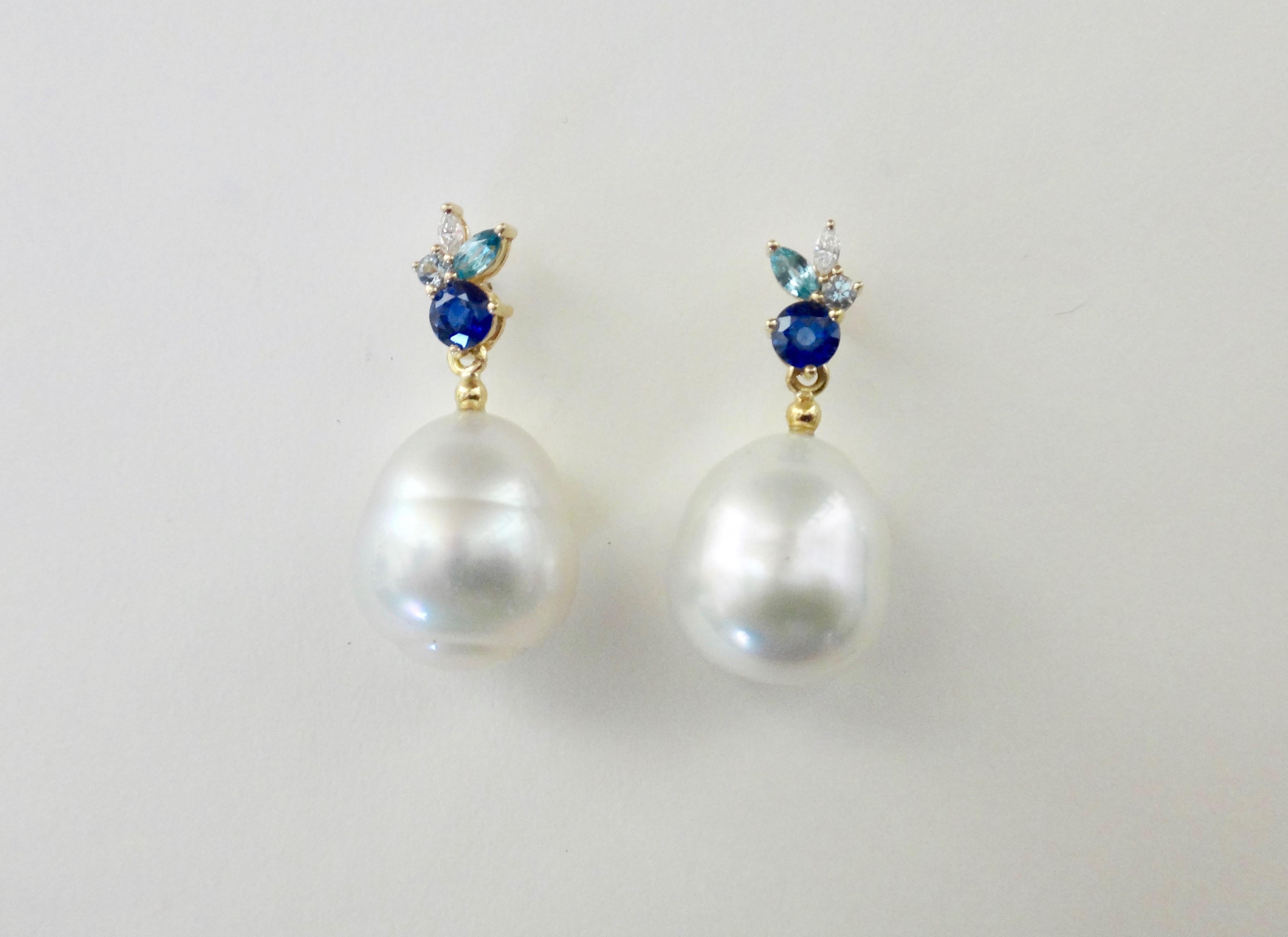 A round cut blue sapphire and aquamarine are combined with marquise cut blue topaz and diamonds in these dainty Confetti earrings.  Dangling below each cluster of gems is a baroque, gem quality Paspaley South Seas pearl.  Set in yellow gold, the