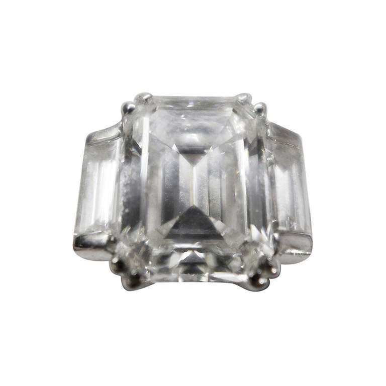 A white gold ring set in the middle with a 3,10 carat emerald cut diamond . 
On each side of the central stone, one baguette cut diamond. 
Baguette cut diamonds weight : 0,75 carat. 
Central diamond quality : F-VS1 
Belgium Gemological
