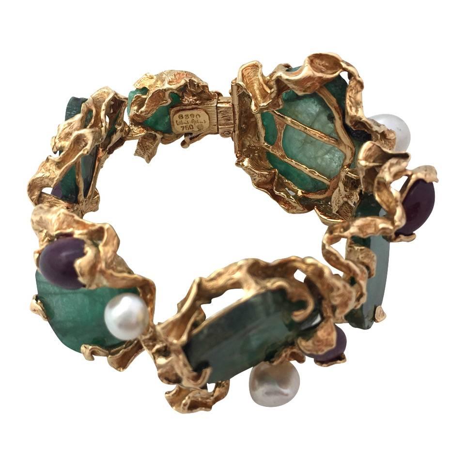A 750/000 yellow gold Gilbert Albert bracelet set with 6 emeralds slides, enhanced with cabochon rubies and baroque shaped white pearls. The claws are made of stylised yellow gold leaves.
Length: 170 mm for a wrist of 15 mm maximum.
Width 42