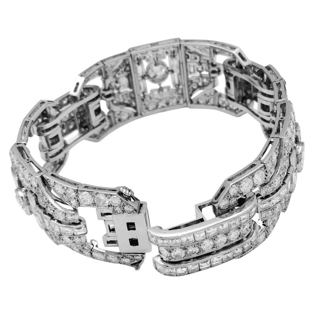 A 950/000 platinum Art Déco period large bracelet, made with six diamonds set geometrical motifs. The three larger ones are centred with an old cut about 0,90 carat diamond, shouldered with baguette cut diamonds and enclosed in an old-cut diamonds