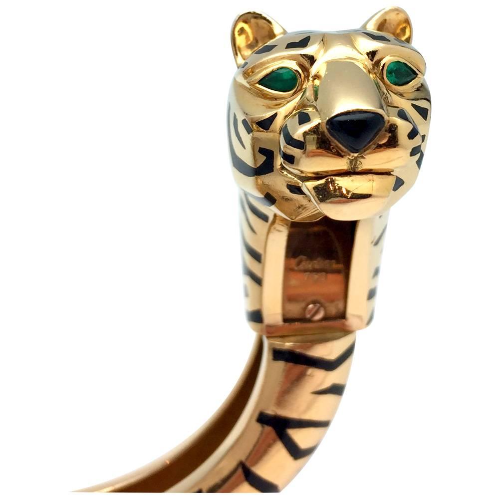 A 18kt Cartier yellow Gold Bangle Bracelet Gengis Khan Tiger collection. 
The eyes are set with emeralds.
Width 22 mm.
Diameter 58 mm.
Height 24 mm.
Weight 150 grammes.
Style Period 1990
