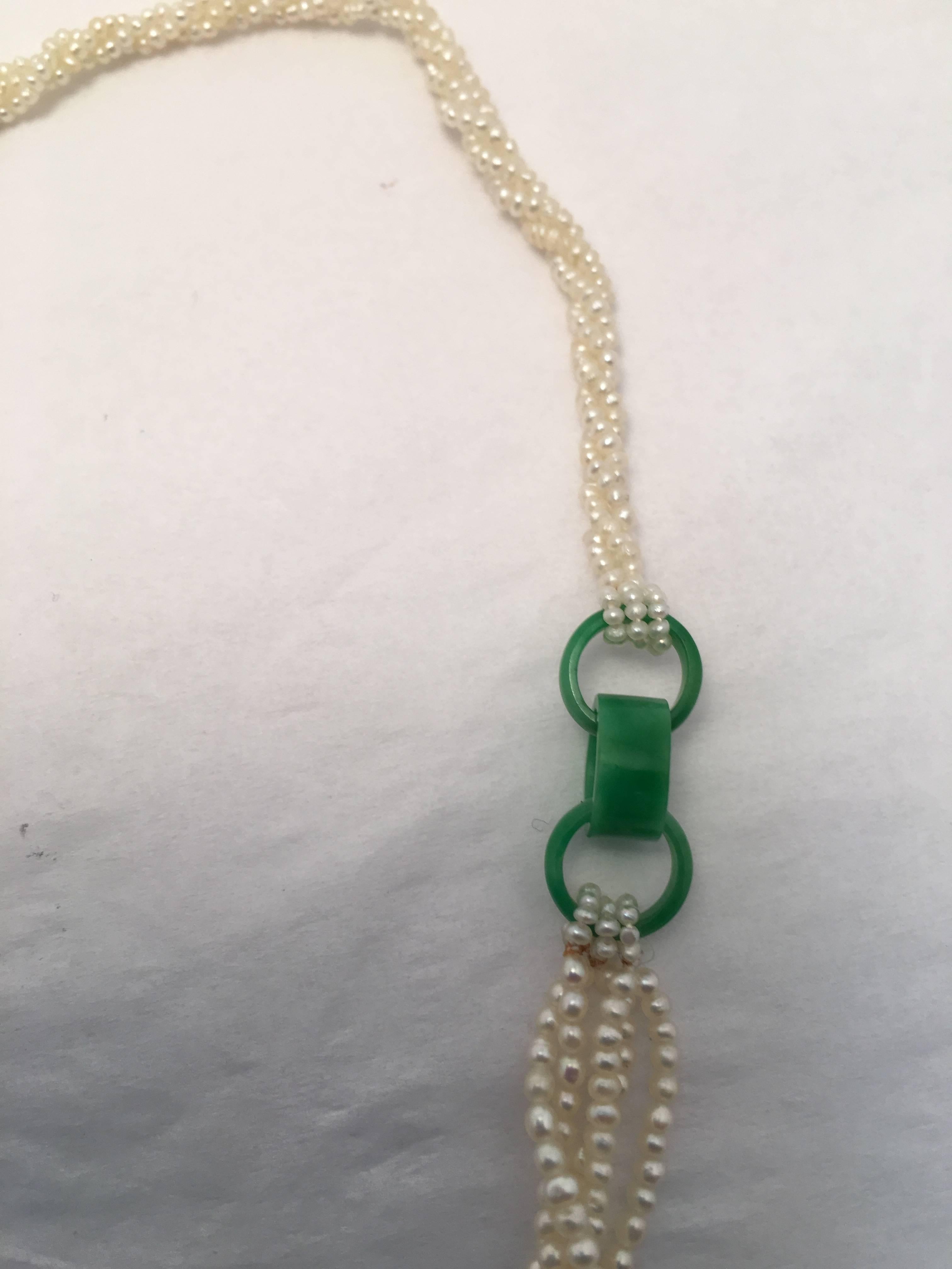 This dainty necklace consists of three twisted strands of natural seed pearls toward the back which attach to three interlocking rings of jade.  The front of the necklace consists of five strands of slightly larger twisted natural seed pearls. 