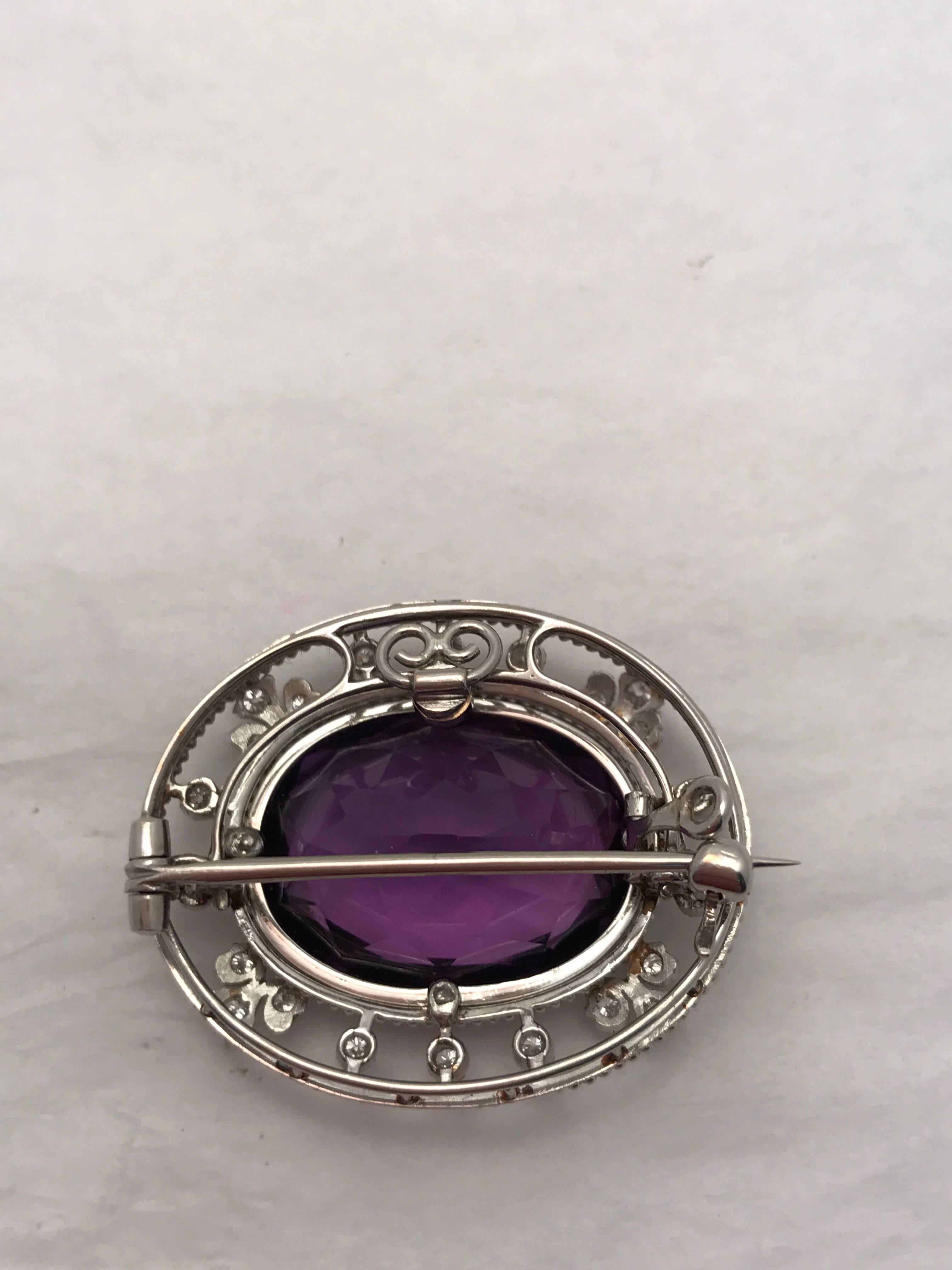 This 18 Kt. white gold pendant/brooch is set with one beautiful oval amethyst surrounded by full cut diamonds in a delicate motif.  Amethyst separates from the frame to become a bezel set pendant which hangs vertically.  