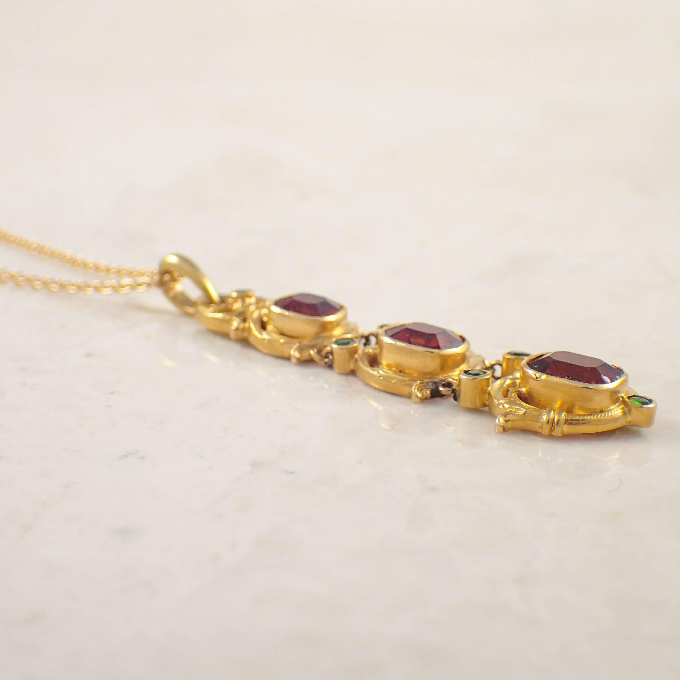 Art Nouveau 14k yellow gold citrine and garnet pendant. The graduated carved links are centered with cushion shaped madeira citrines, accented by small round demantoid garnets. The 1.75 inch drop is suspended by a 16 inch cable chain. Gold weight