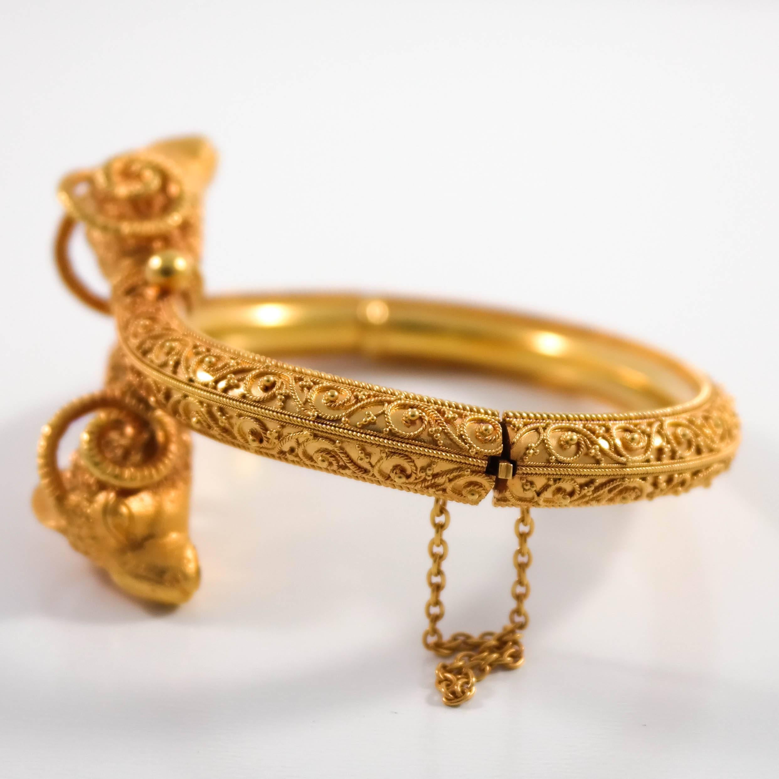  14k yellow gold Etruscan revival rams head bangle bracelet. The bypass rams head motif decorated with very fine wire, and bead work, with a hinged opening, and safety chain that was added at a later date. The bracelet is in very good condition,