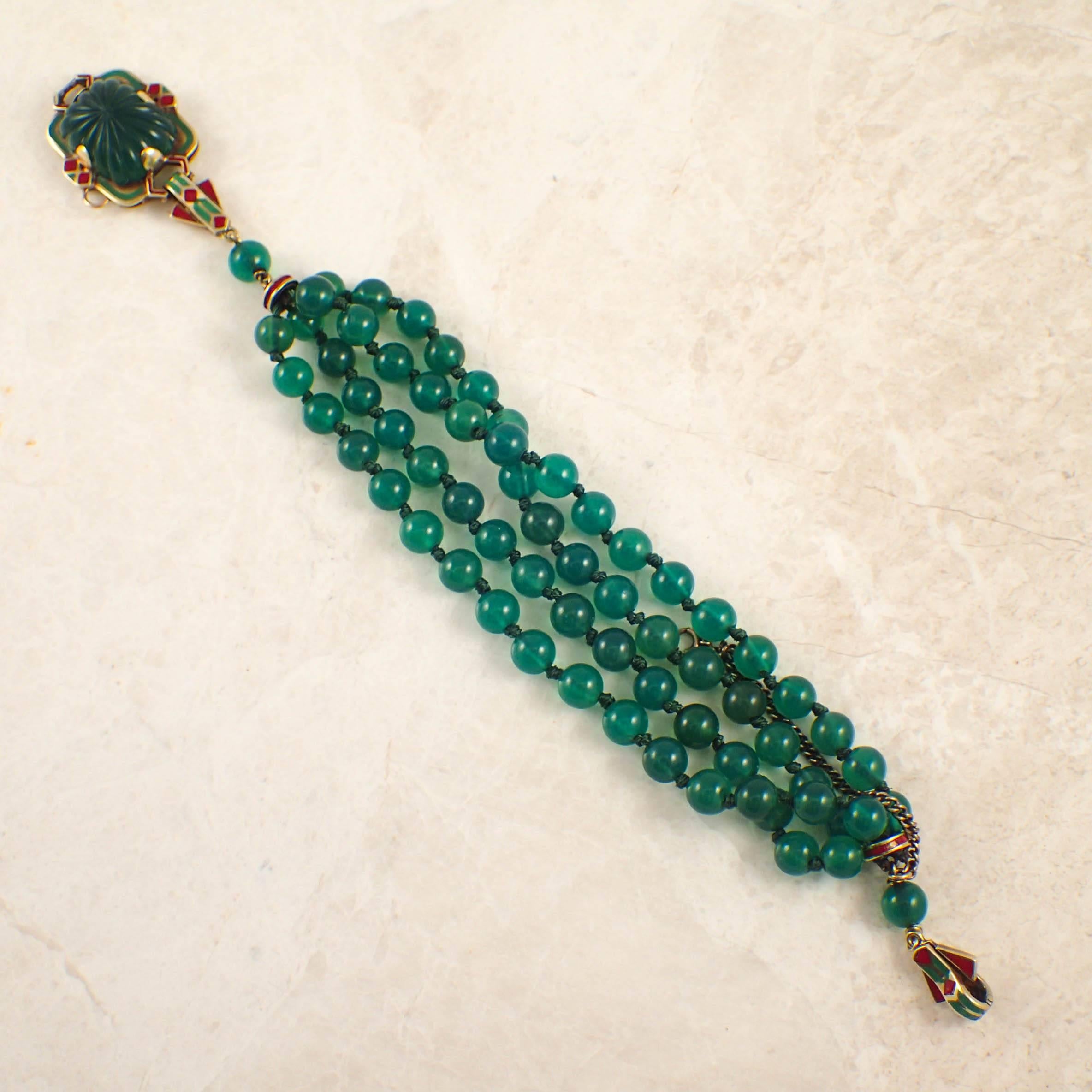 14k yellow gold Art Deco green onyx and enamel bracelet. The multi strand bead bracelet composed of green onyx beads measuring approximately 6.5mm, finished with a carved green onyx measuring 18.5x14mm, set into the clasp, and decorated with red and