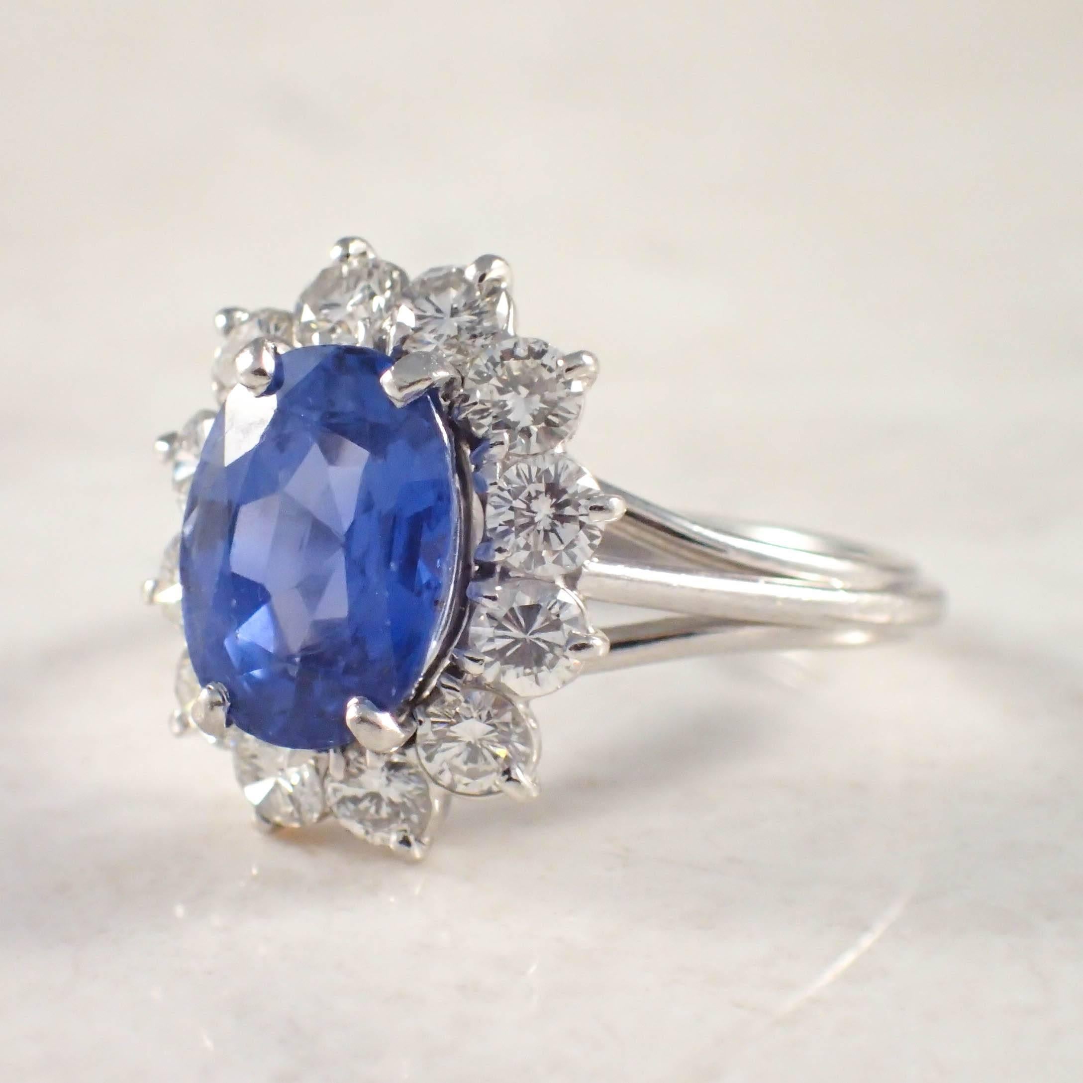 Platinum Natural sapphire and diamond ring. The cluster style set with one oval Ceylon sapphire weighing 2.63 carats, surrounded by 12 round diamonds weighing approximately 1.00 carat total. The ring is stamped platinum, and an acid test was also