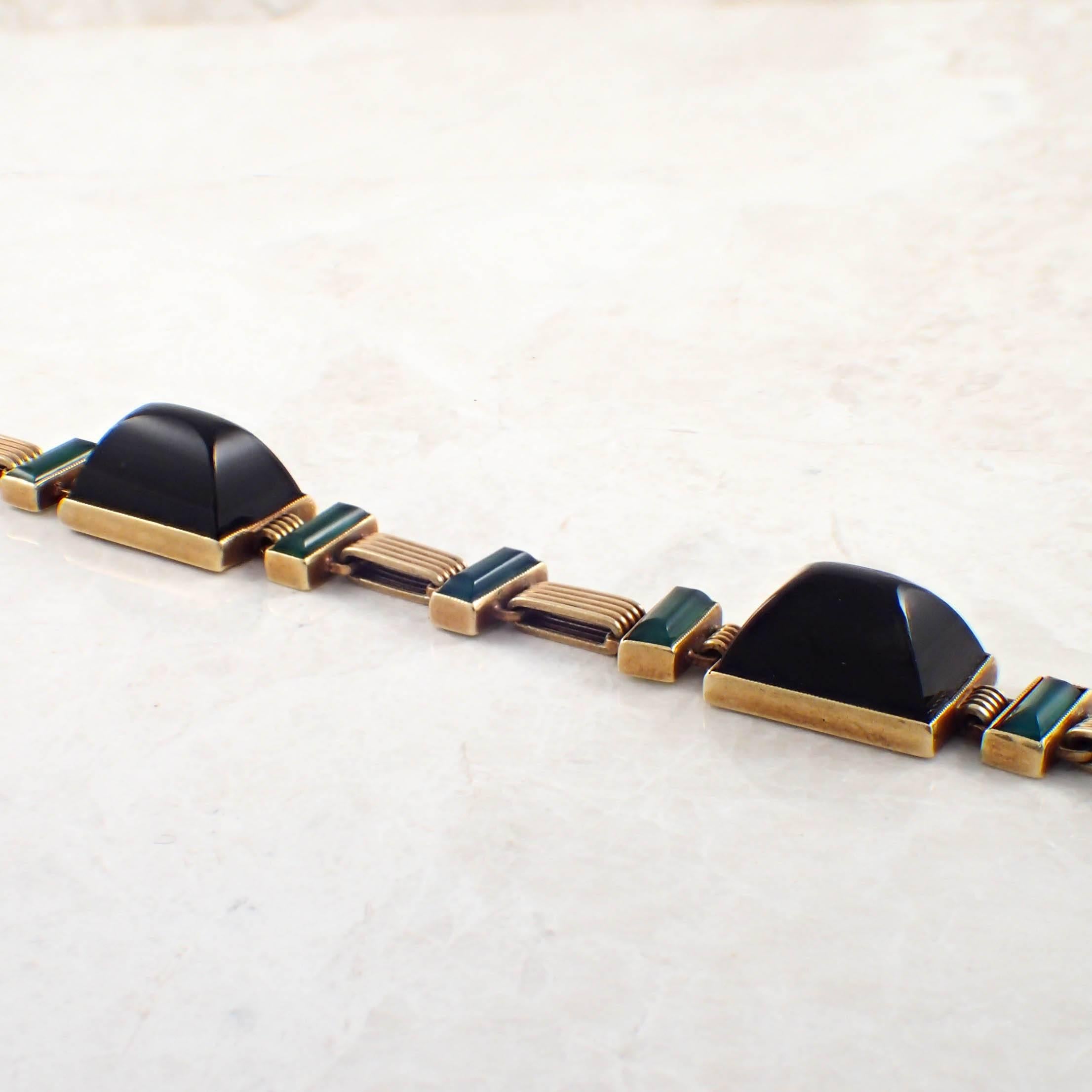 14K Yellow gold Art Deco onyx bracelet. The bracelet alternates sugarloaf cabochon black onyx and emerald cut green onyx sections. The bracelet measures 12.7 mm and 7 inches long. Gold weight 15 DWTs. Circa 1920s.