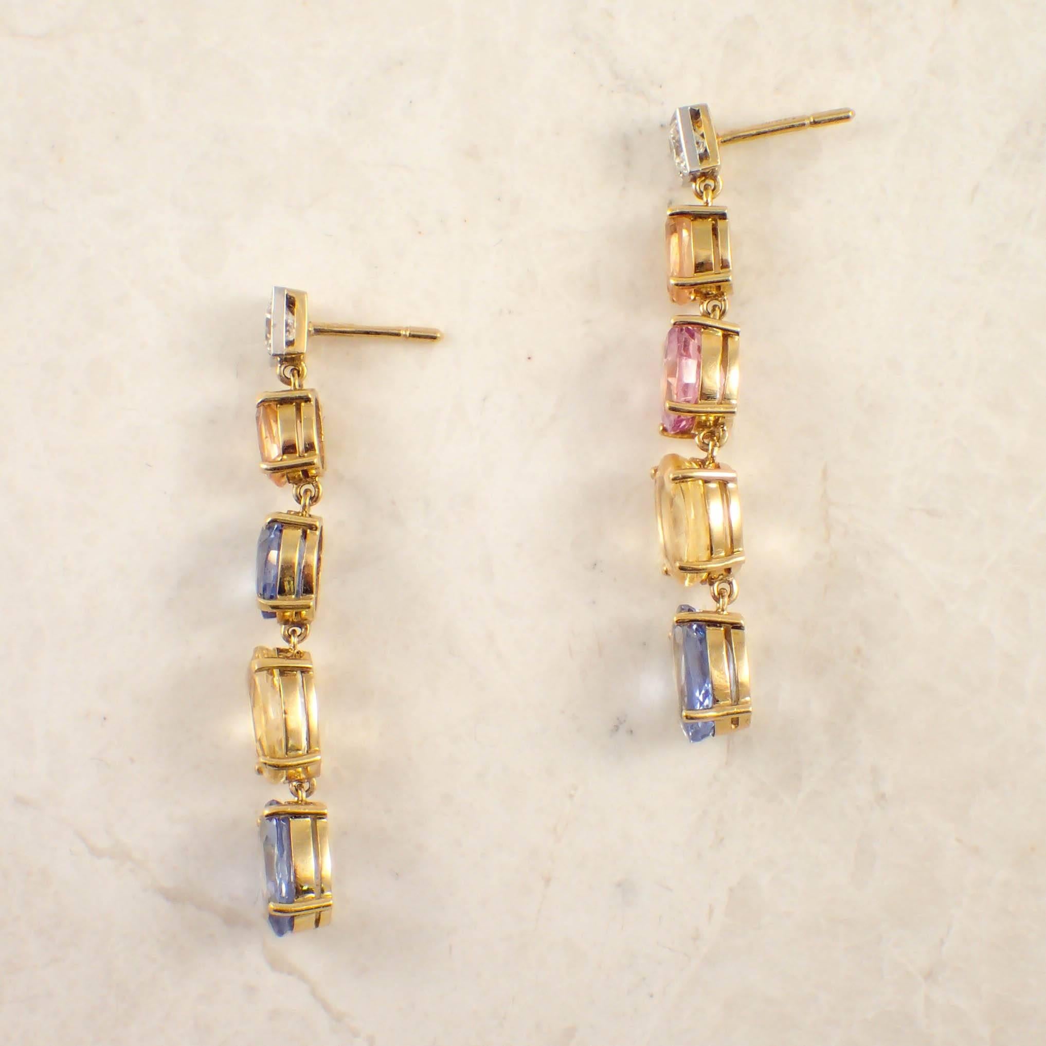 18K White and yellow gold multicolor sapphire and diamond earrings. The drop earrings are set with 2 round diamonds weighing approximately .60 carat total, each suspending 8 oval sapphires weighing approximately 11 carats total. The drops measure 2