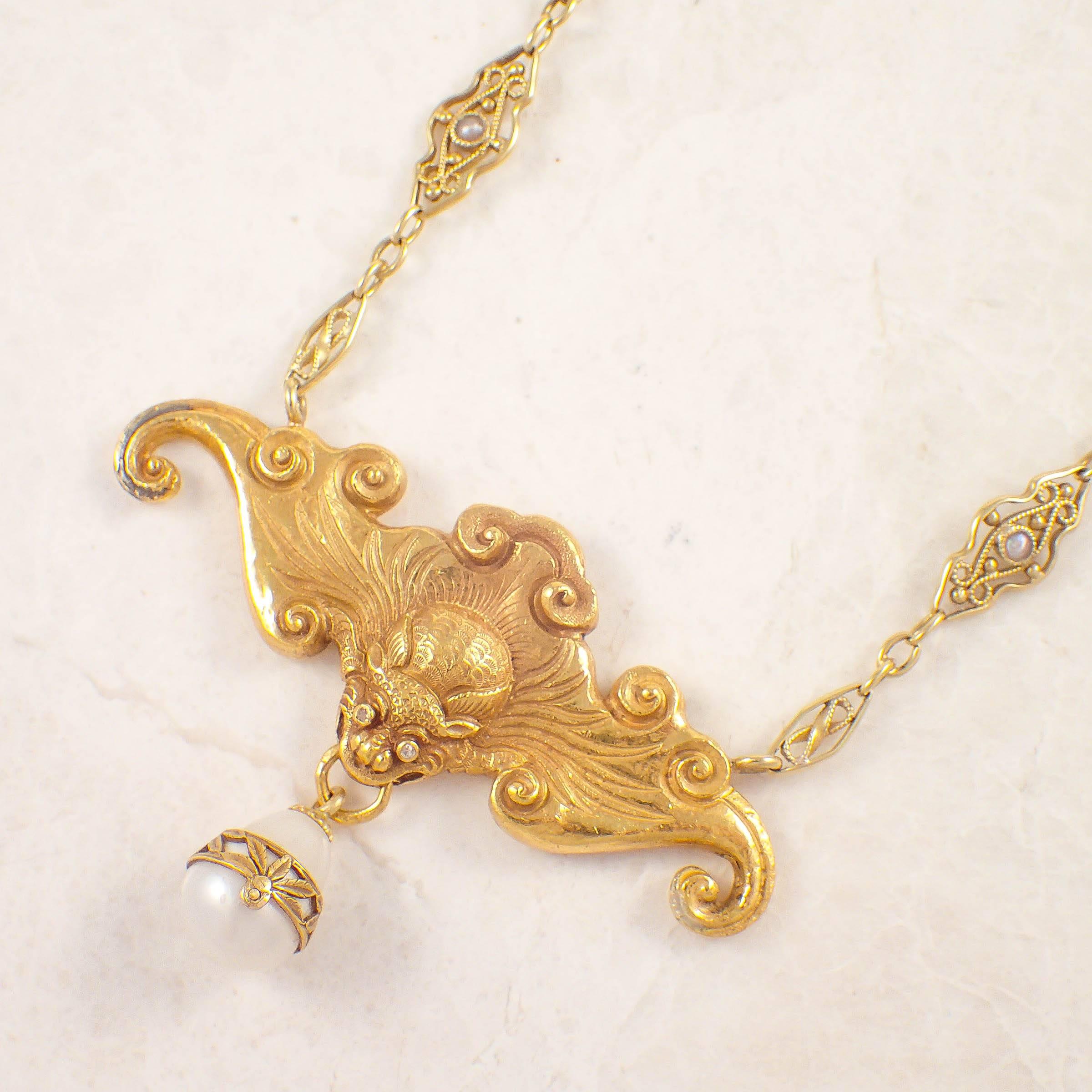 Art Nouveau 18k yellow gold bat necklace. The fancy link chain is set with small seed pearls. Suspended from the chain is a flying bat center piece with a pearl dangling from its mouth. Circa 1900s.