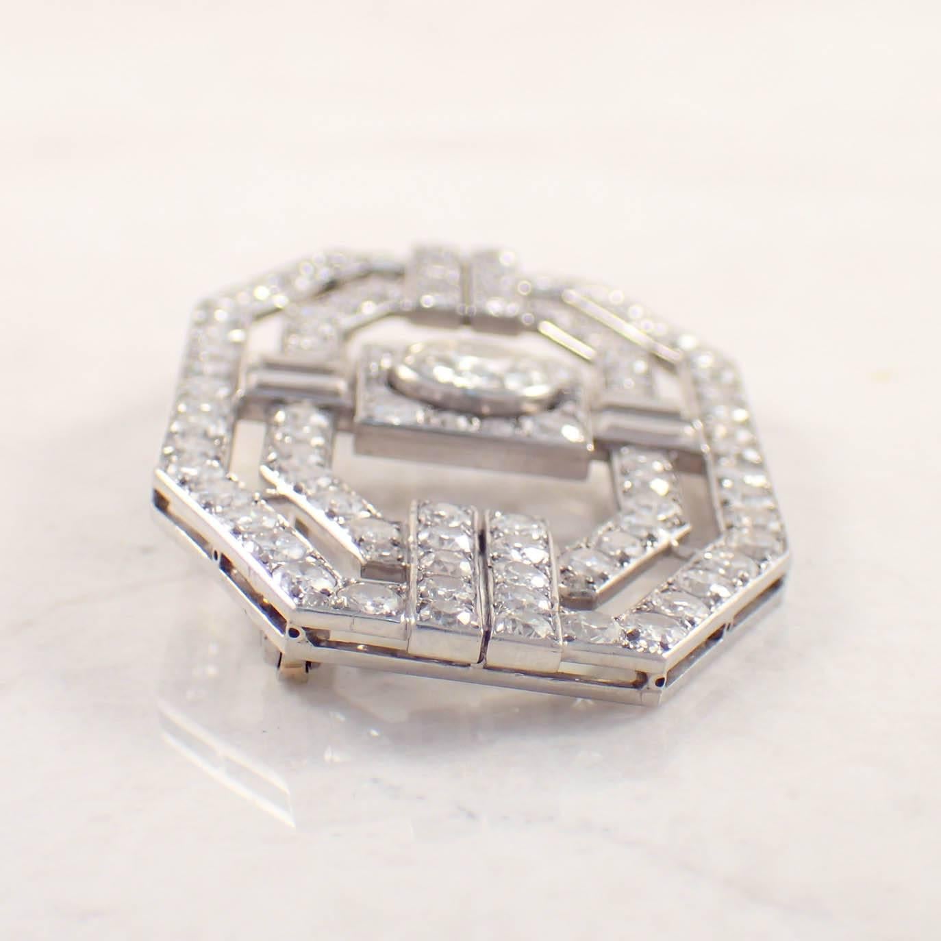 Art Deco diamond platinum La Cloche brooch. The open work, shield shaped brooch is centered by 1 collet set European cut diamond weighing approximately 1.40 carats, surrounded by 104 round diamonds weighing approximately 7.00 carats total and 4