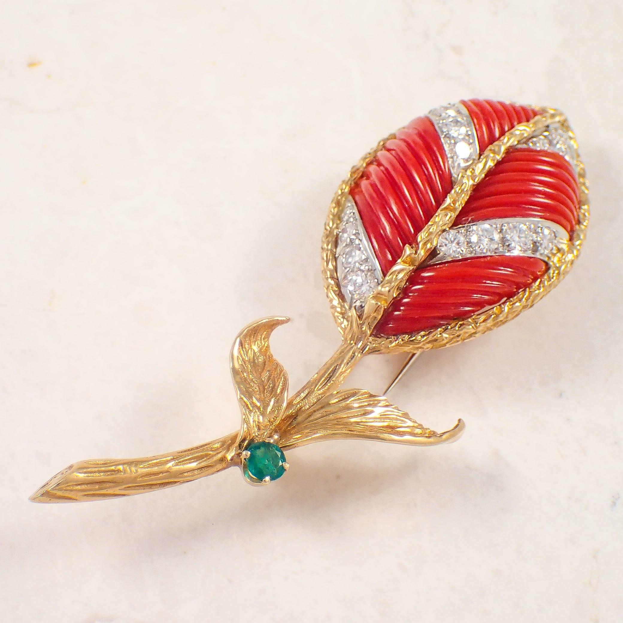 18K Yellow gold and platinum coral, diamond and emerald brooch. The carved oxblood coral leaf brooch is pave set with 16 diamonds weighing approximately 1.00 carat total and one round emerald measuring 3.5 mm. The brooch measures 3 X 1 inches and