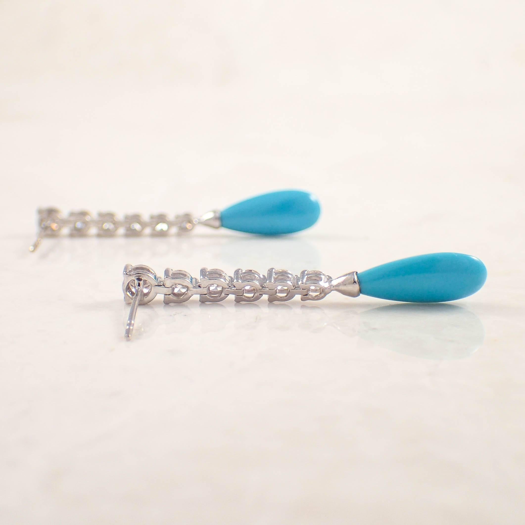 18K White gold diamond and turquoise pendant earrings. The flexible earrings are set with 2 tear drop turquoises suspended by 12 graduated diamonds weighing approximately .85 carat total. The earrings measure 1 1/2 inches long and weigh 3.5