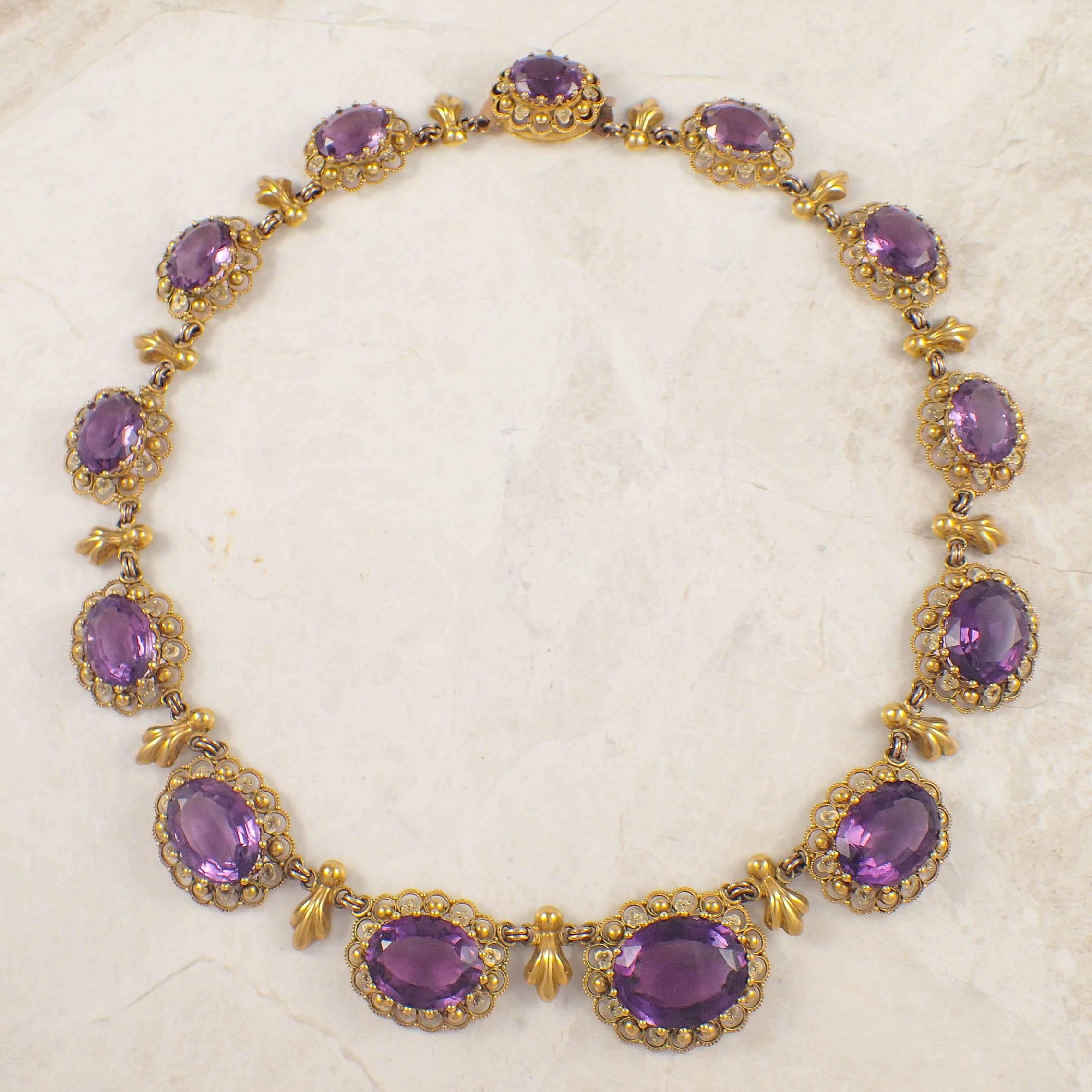 Antique 14k yellow gold amethyst necklace. The necklace is set with 13 graduated oval amethysts measuring from 20 X 15 mm to 12 X 10 mm. Each stone is set within an open work, twisted wire and granulated frame. The sections are connected by a