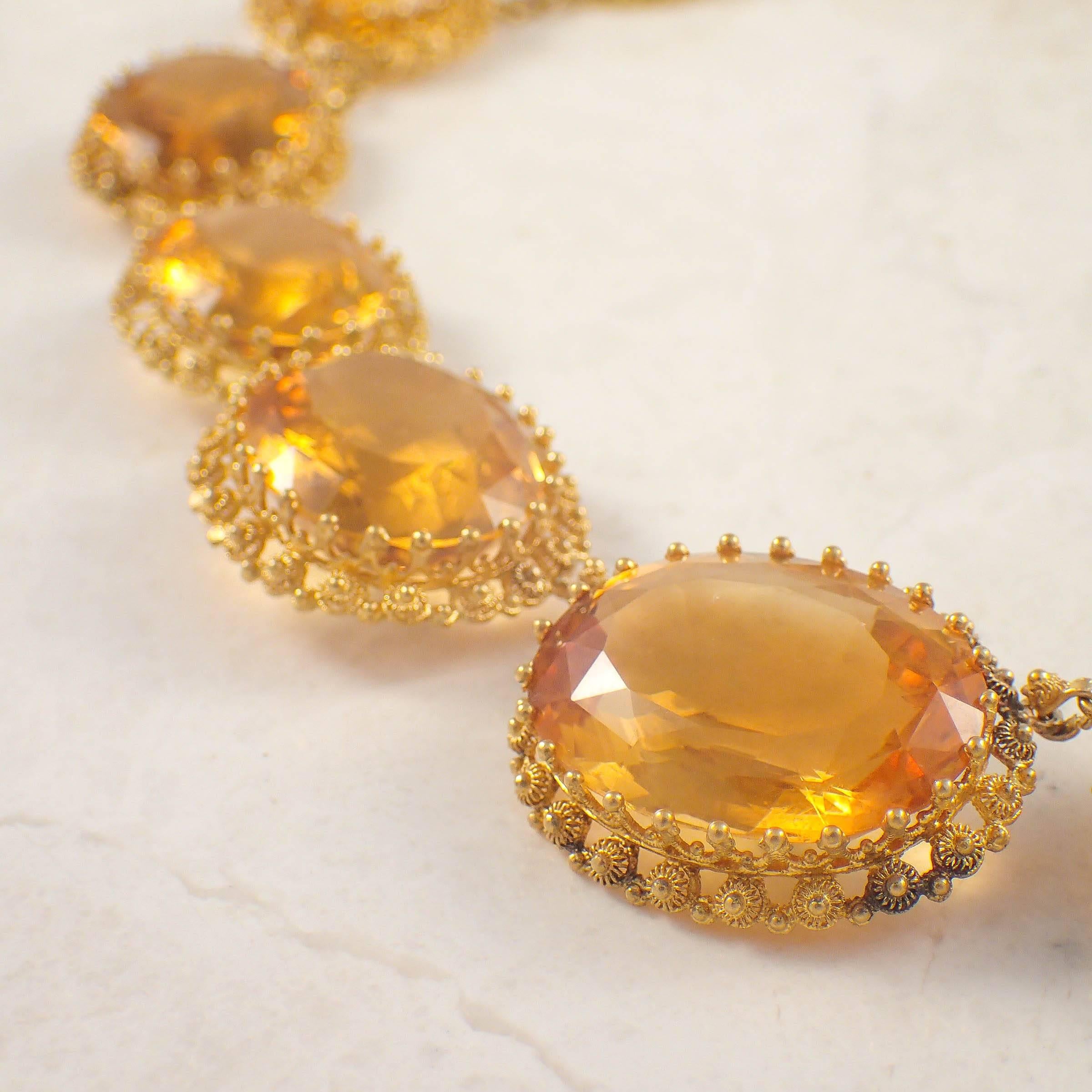 Antique 14k yellow gold citrine necklace. The necklace is set with 19 graduated oval citrines measuring 21.8 X 16.5 mm. Each stone is set within an open work, granulated frame. The necklace measures 16 inches long.   
Circa 1830s