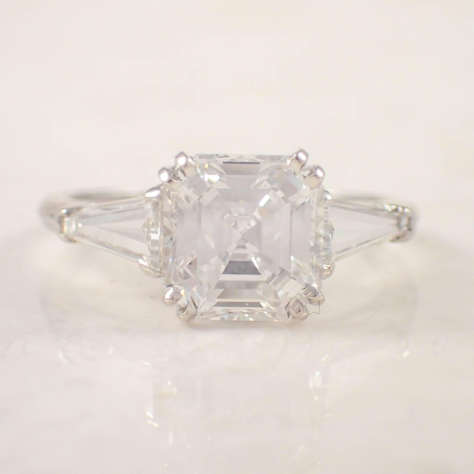 Platinum diamond engagement ring. The three stone prong ring is centered with a GIA certified, 2.09 carat Asscher cut diamond, accented by 2 tapered baguettes weighing approximately 30/100 carat total. The ring weighs 3.7 grams. 

GIA
Color: