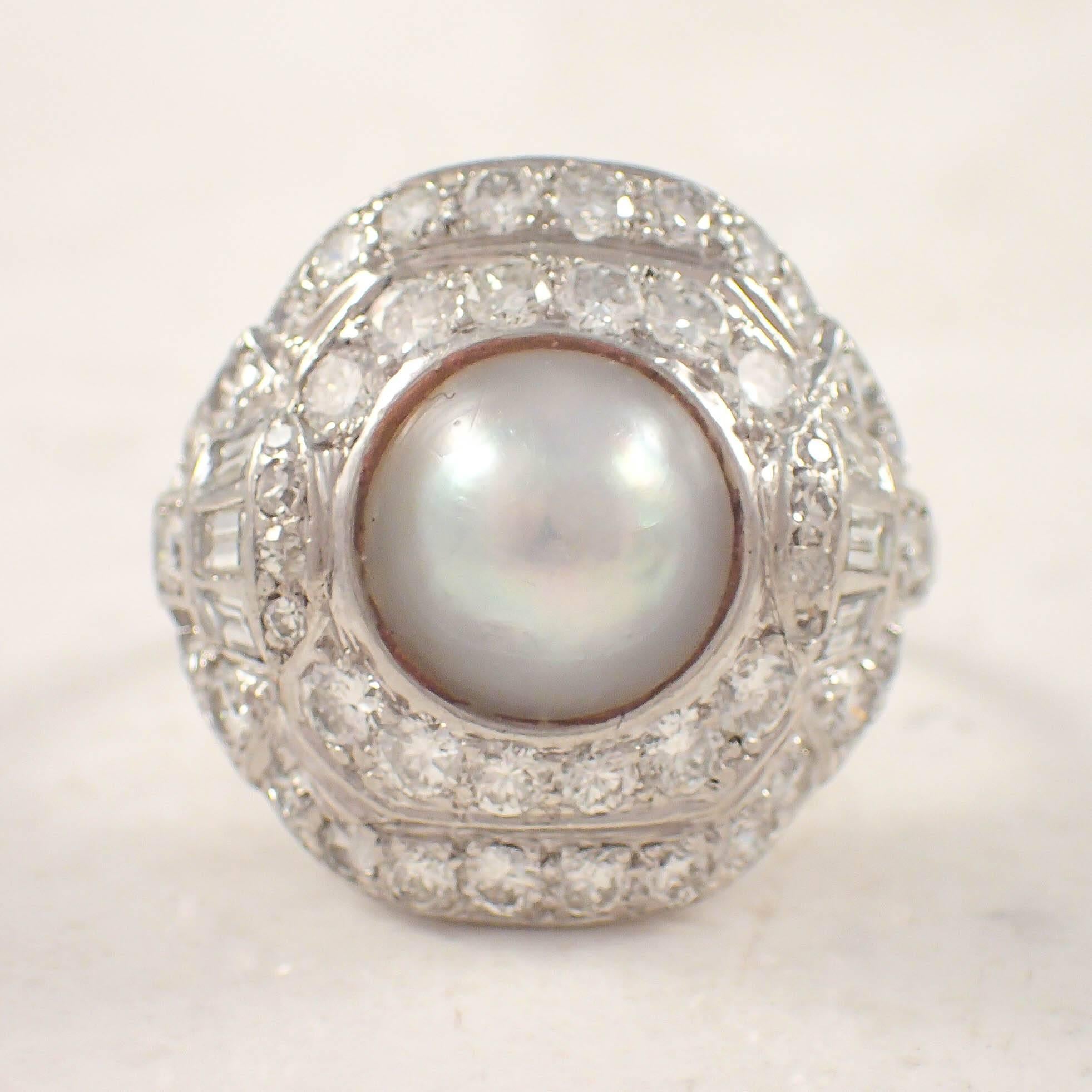 Art Deco platinum pearl and diamond ring. The domed top is set with a half pearl measuring approximately 8 mm, surrounded by 60 small round diamonds and 6 small baguette diamonds weighing approximately 2.00 carats total. The ring weighs 6.5 grams.