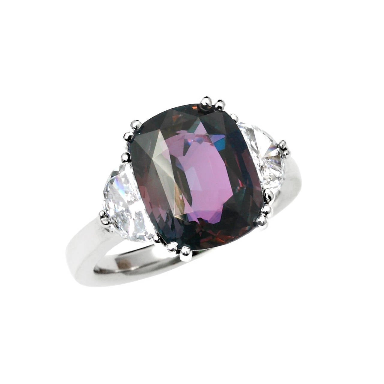A beautiful and classic three stone ring set with a 7 ct+ cushion-shape natural Alexandrite measuring 12.34 x 9.99 x 6.52 mm accented with two brilliant cut half-moon diamonds weighing an estimated total of 0.86 carats, set in Platinum. The