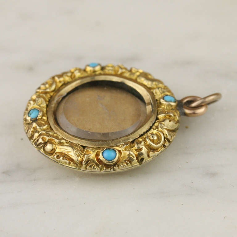 - Antique Chased Floral Locket
- c. 1790-1830
- 15k yellow gold, turquoise

A lush and heavy example of the luxurious, ornate styles popular in the Georgian period, this 15k yellow gold locket features a turquoise-studded floral wreath motif.
