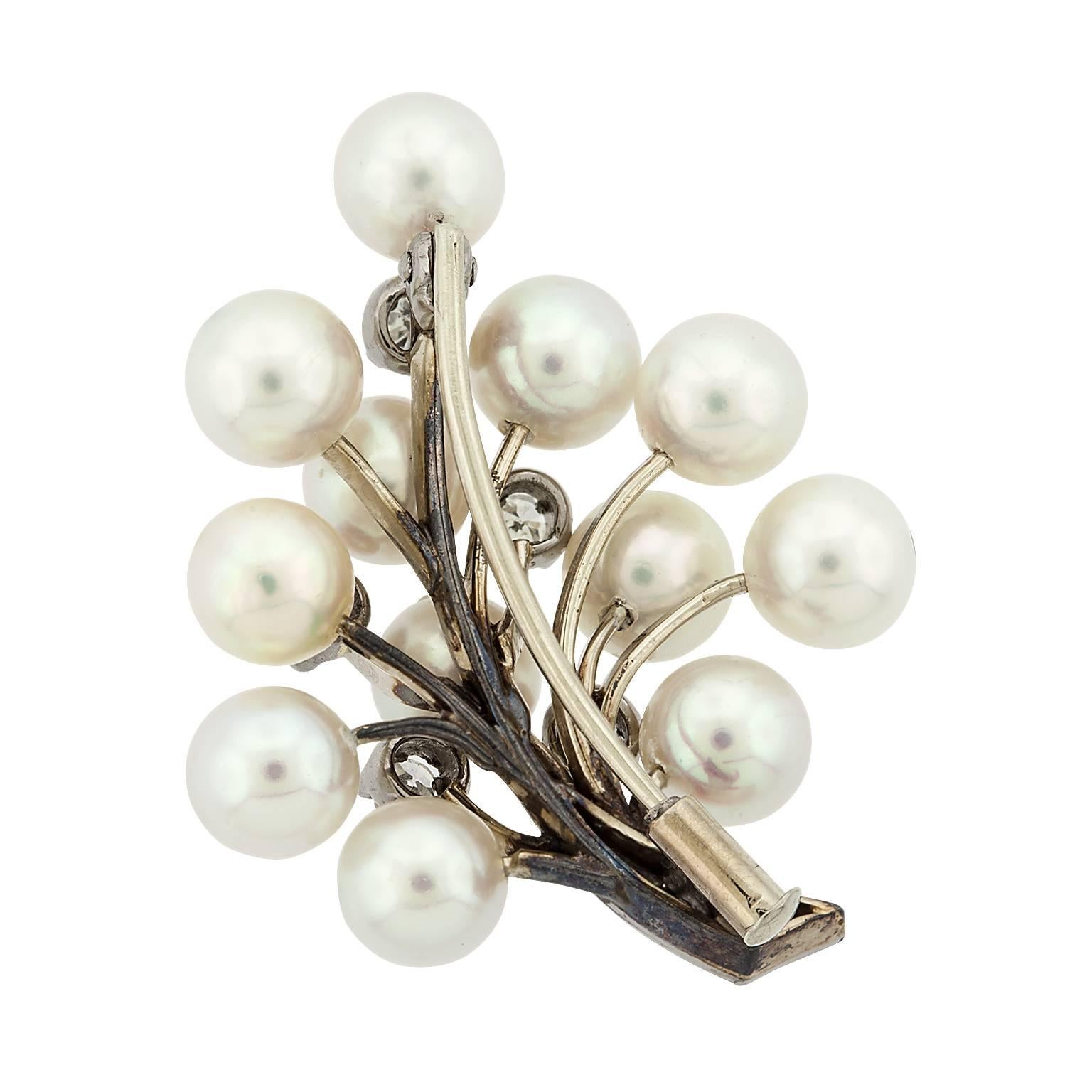 A cultured pearl and round diamond 18 karat white gold leaf brooch.  The pearls are set on posts branching out from the center, with five diamonds scattered throughout, and a diamond stem.  The pearls average 6.00 x 6.50 millimeters.  The diamonds
