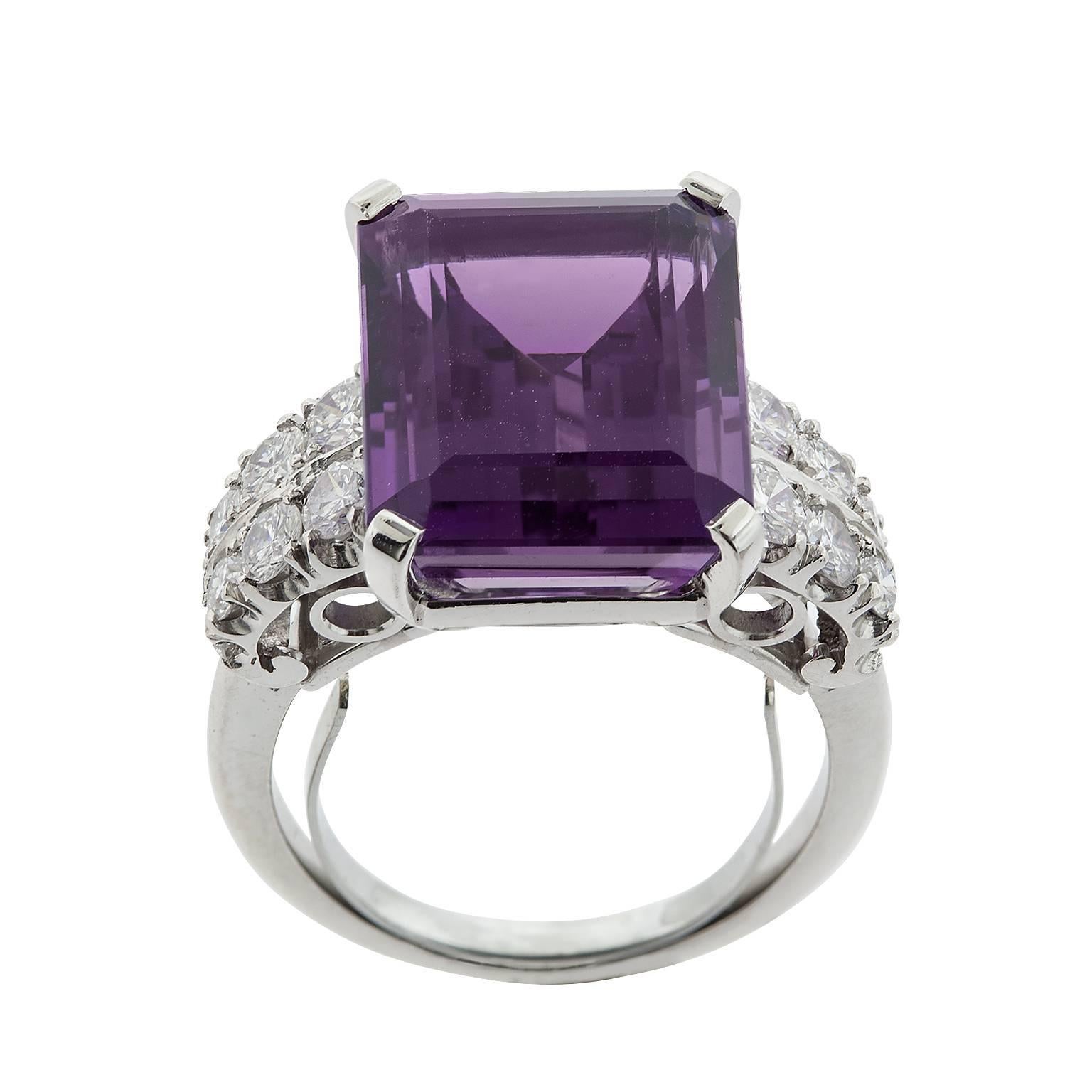 A 10.54 carat emerald cut amethyst and round brilliant diamond ring set in platinum.  The amethyst is set in a four prong basket, with a double row of diamonds on either side.  The diamonds are graded as G color, VS clarity, and have a total weight