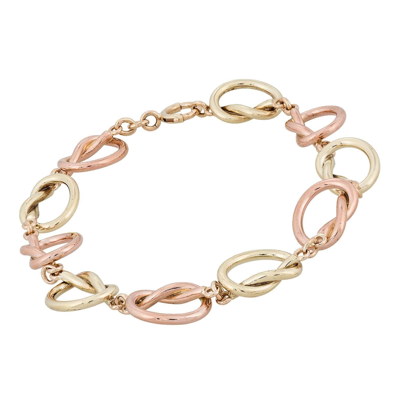 Love knots 14 karat green and rose gold bracelet.  A series of heart shaped knots, alternating from green to rose gold.  8.00 inches in length.  