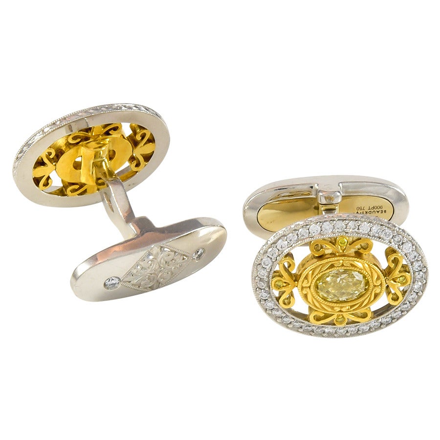 Thes are a fabulous pair of cufflinks!  There are two bezel set oval fancy yellow diamond centers that have a total weight of .96cts, surrounded by 18k yellow gold fleur de lis, and bordered with .48cts total in round brilliant diamonds and