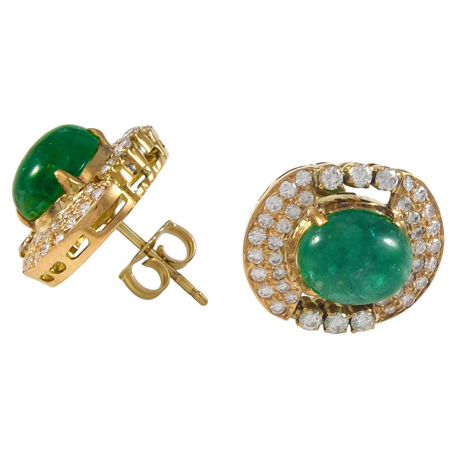 A pair of cabochon cut rich green emerald and diamond earrings set in 18k yellow gold. The two emeralds have an estimated combined weight of 5.00cts.  The surrounding round brilliant cut diamonds have an estimated total weight of .92cts.