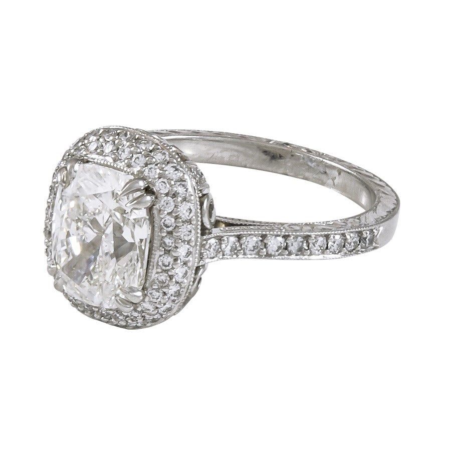 2.11 carat cushion shape diamond with pave halo and hand engraved platinum ring.   The cushion is set with four double prongs, atop a double row pave diamond halo, with four single rows of diamonds on the gallery, and a halfway around diamond shank.