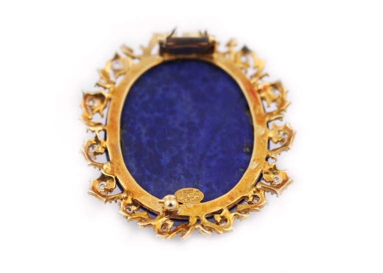 A stunning white opal, lapis lazuli, diamond and gold cameo brooch by La Triomphe.  The carved opal displays all the colors of the rainbow, mounted to the flat oval shaped lapis lazuli, set in a 18kt yellow gold and diamond frame.  The round
