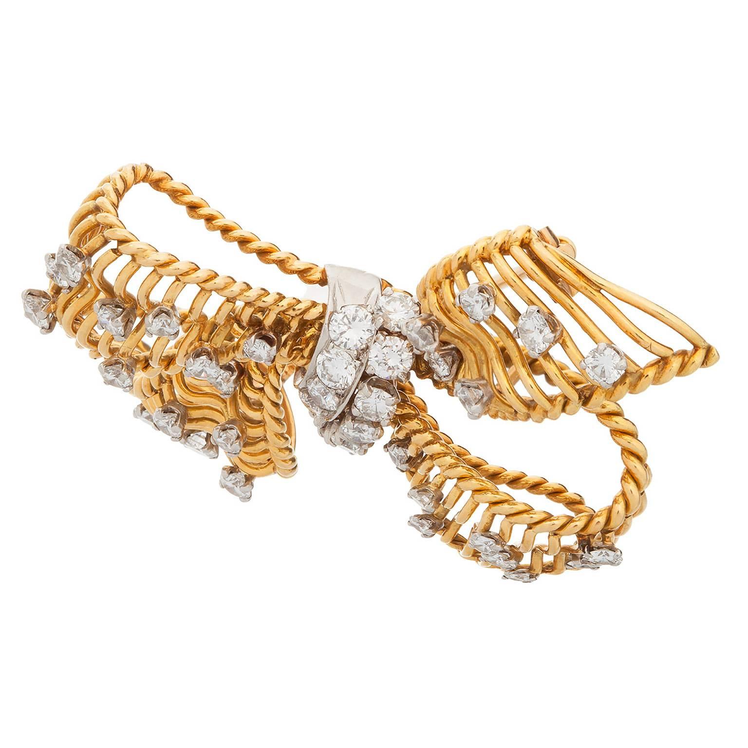 A wonderful diamond bow brooch designed by Bulgari.  The estimated 2.00cts total in round brilliant cut diamonds are set in 18K yellow and white gold, with an open work design.  The diamonds are graded as F-G color, VS clarity.

Signed: 
