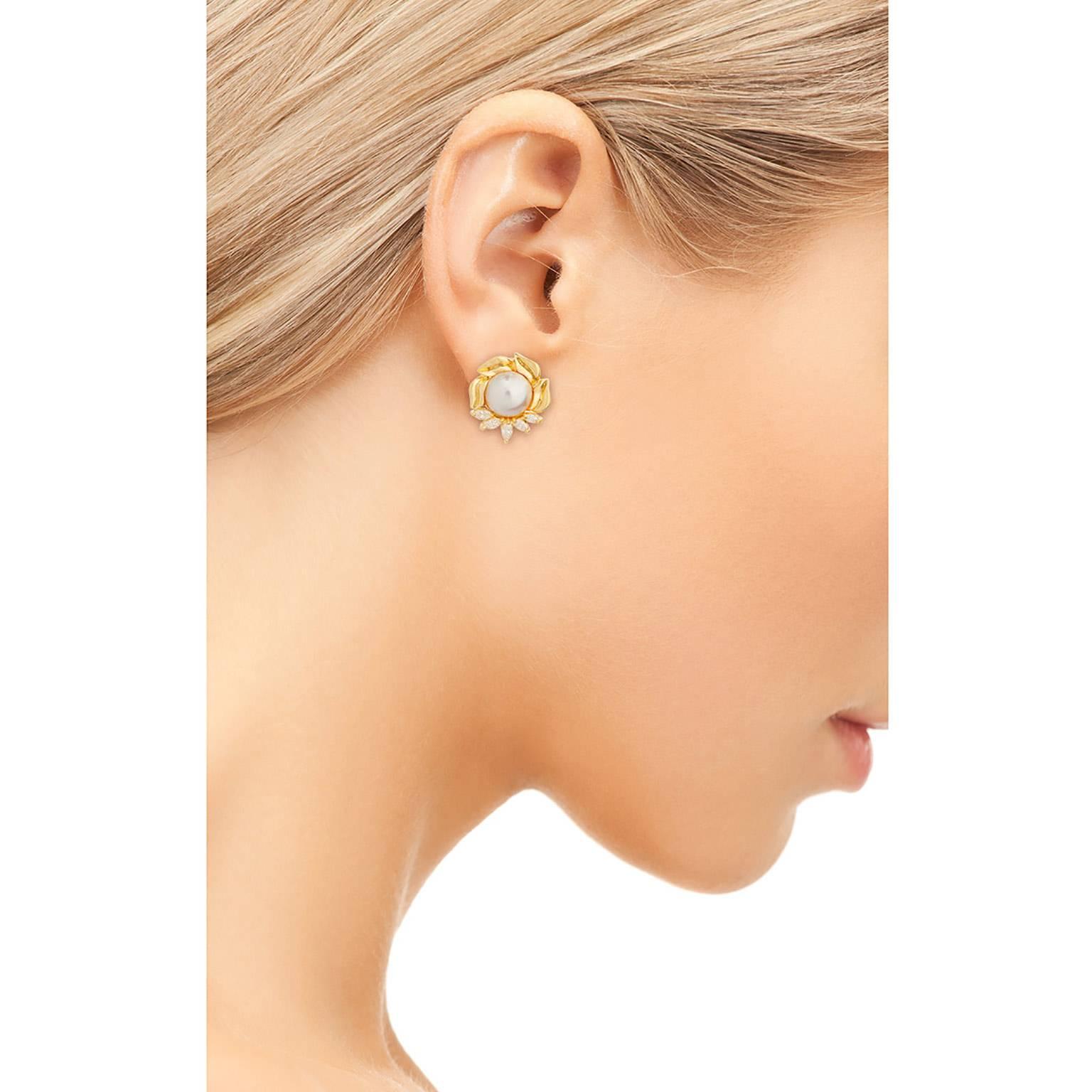 A beautiful pair of mabe pearl and diamond earrings in 18K yellow gold.  The 13mm pearls are in a frame of marquise diamonds and gold leaf design.  te diamonds have an estimated total weight of 1.10cts.  They are graded as G-H color, VS